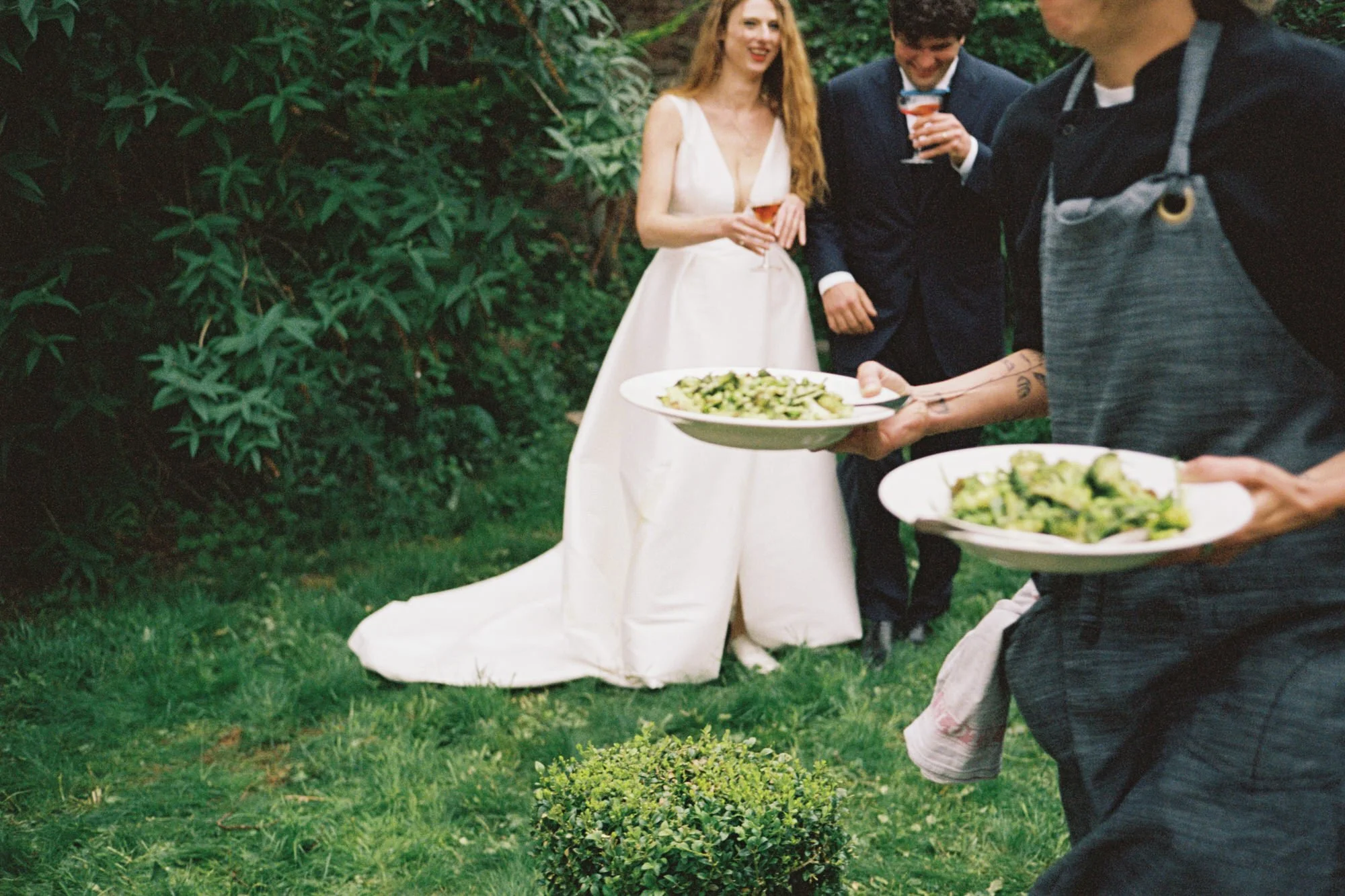 Wedding caterers serving plates beside the newlyweds outdoors