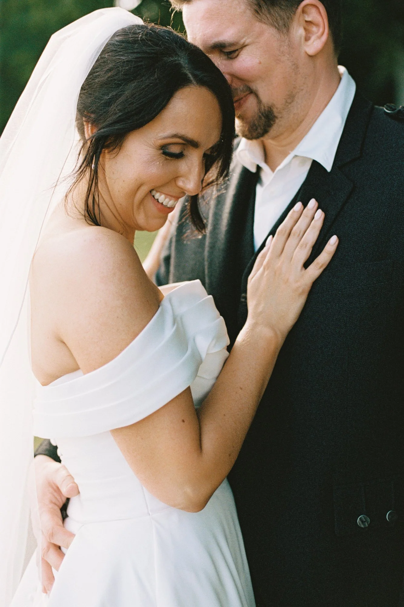 A bride and groom share an intimate moment, smiling with their foreheads touching; the bride's hand rests on the groom's chest, and the groom has his hand around her waist. Photographed by Steven William Weir, Edinburgh Scotland.