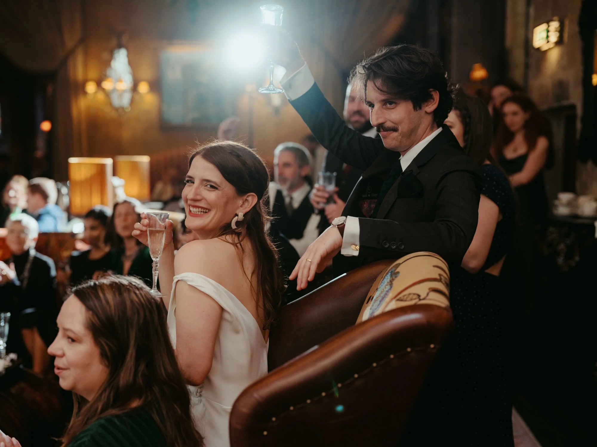 People celebrating at a formal event, with a woman smiling holding a glass of champagne and a man raising a glass of champagne. Photographed by Steven William Weir, Edinburgh Scotland.