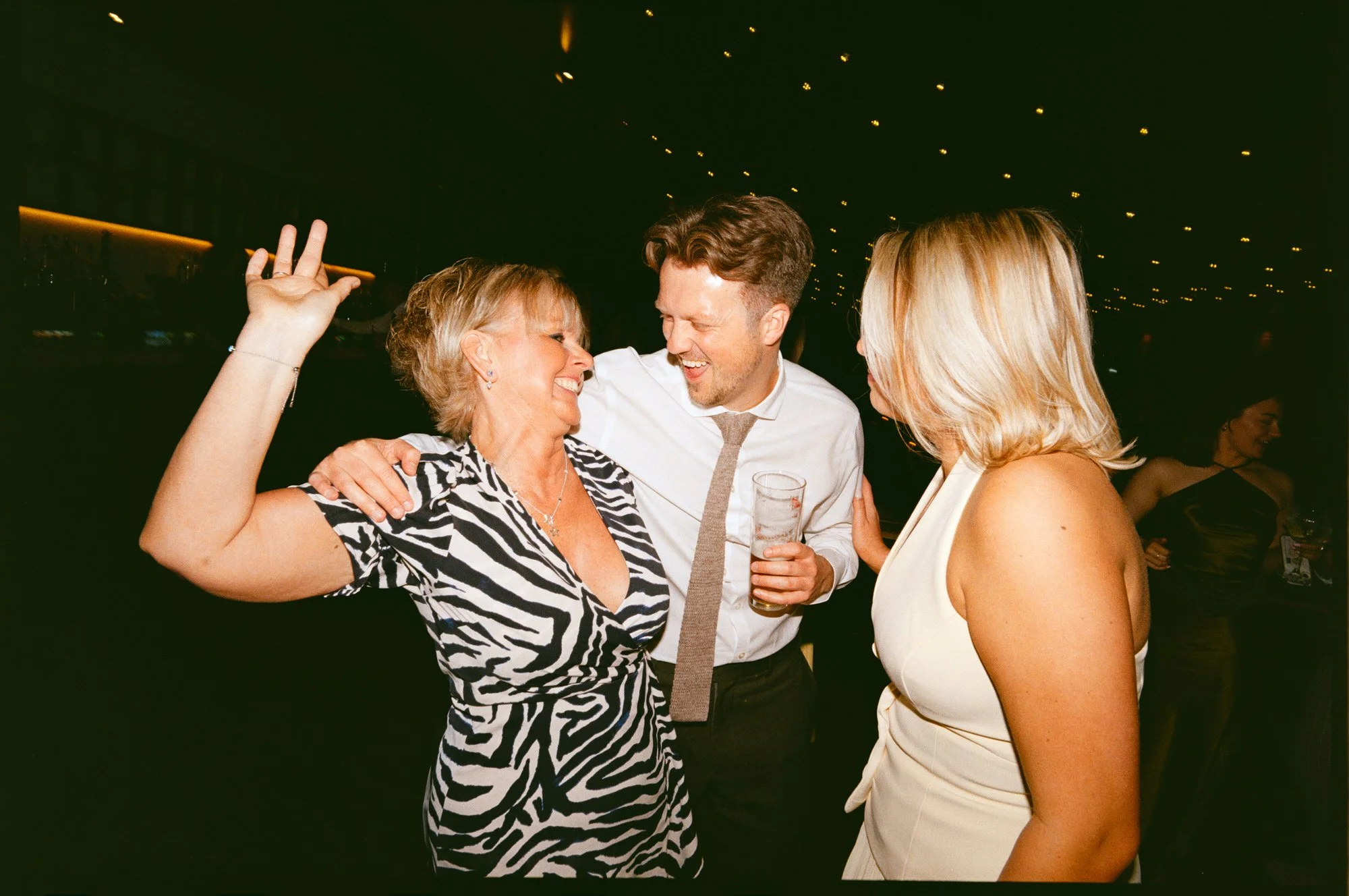 Hazel and Ally celebrating with friends beneath the lights at The Engine Works