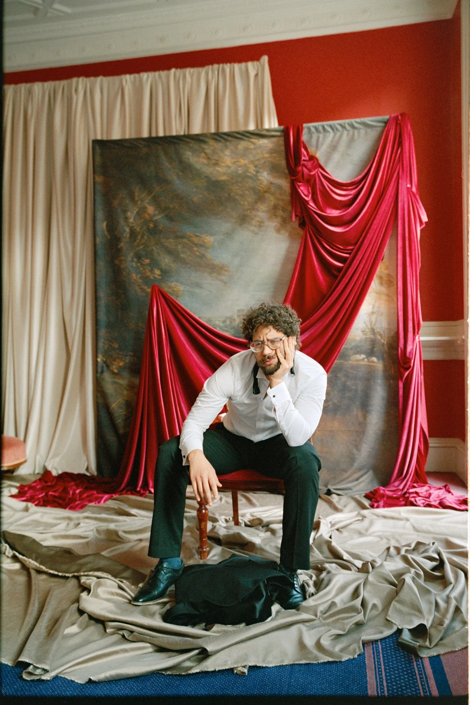 Behind-the-scenes set preparation with red draping and theatre performers