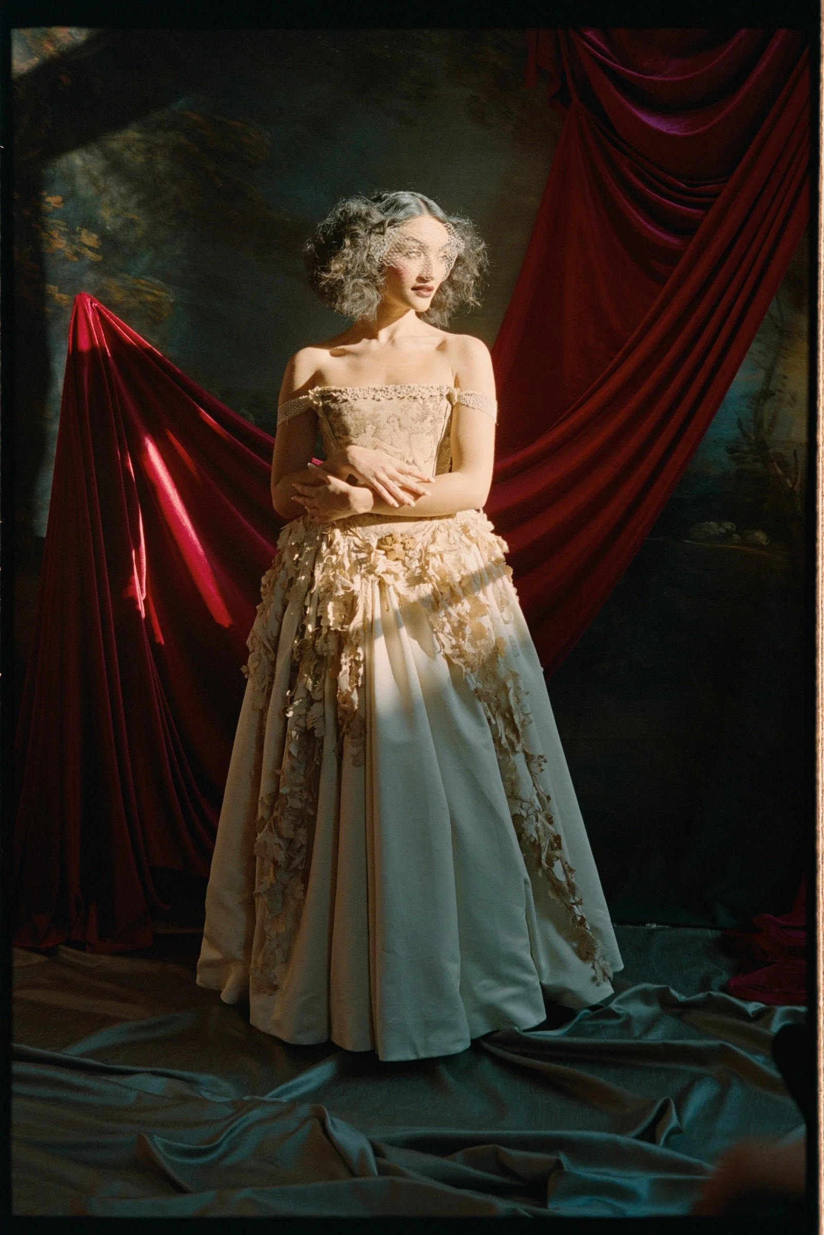 Female performer standing against red theatre curtains in Edinburgh