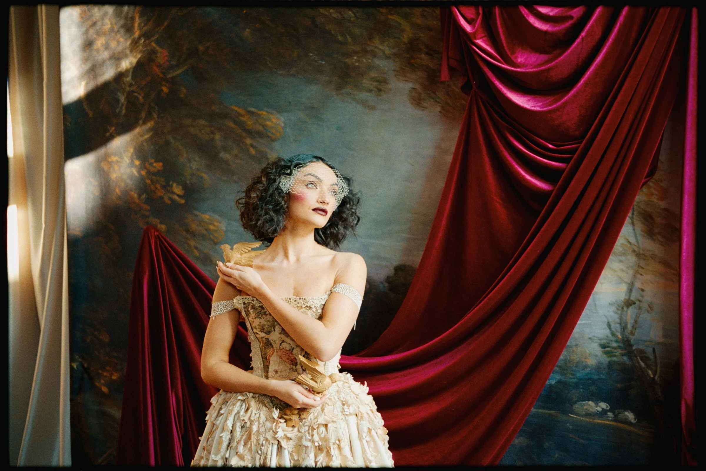 Close portrait of a performer in an embroidered gown against red draping