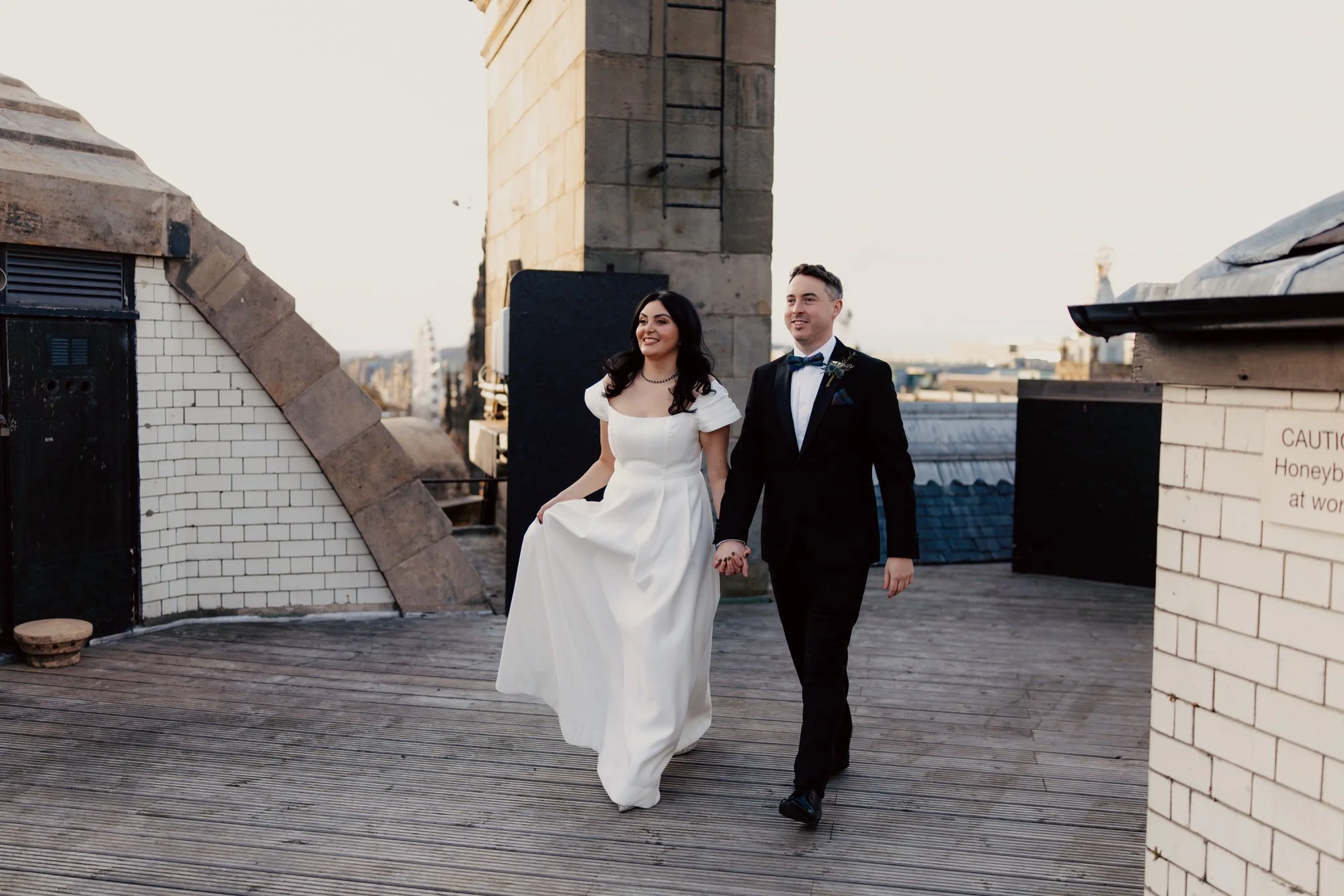 Milly and Vincent walking hand in hand across the hotel rooftop.
