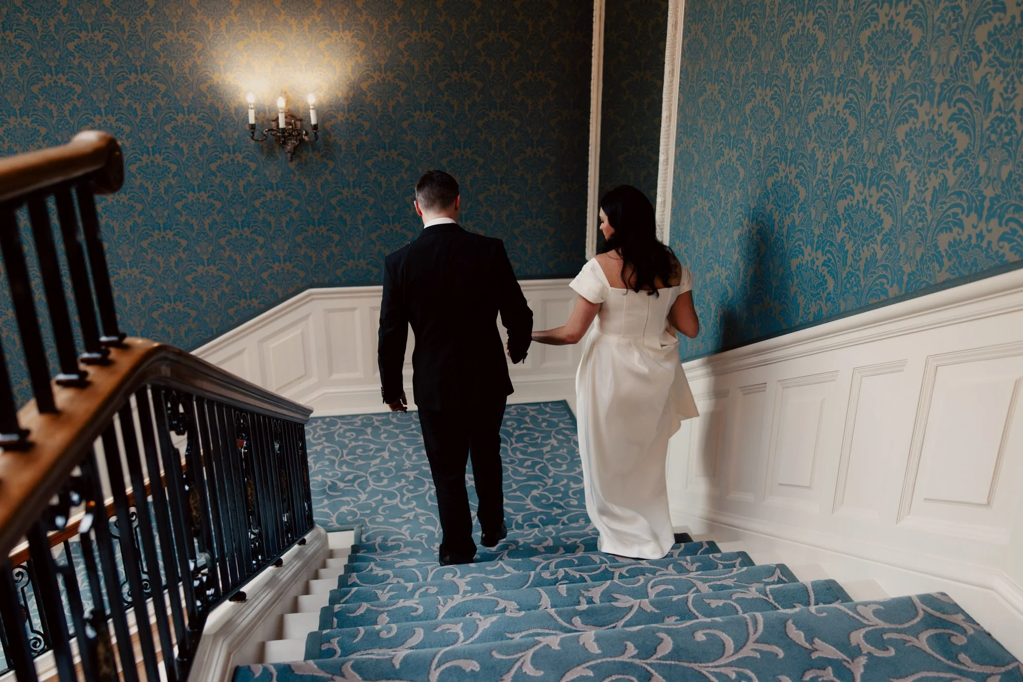 The couple walking down the Balmoral’s blue-carpeted staircase.