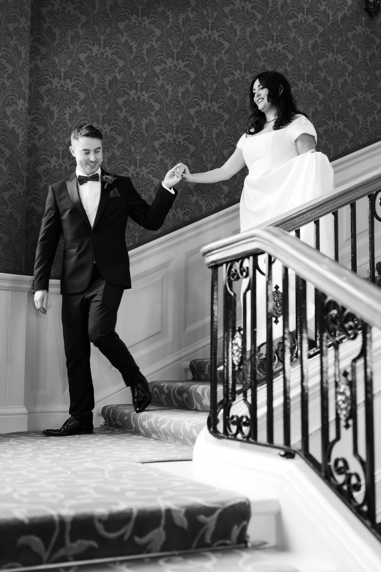 Milly and Vincent holding hands on the stairs.