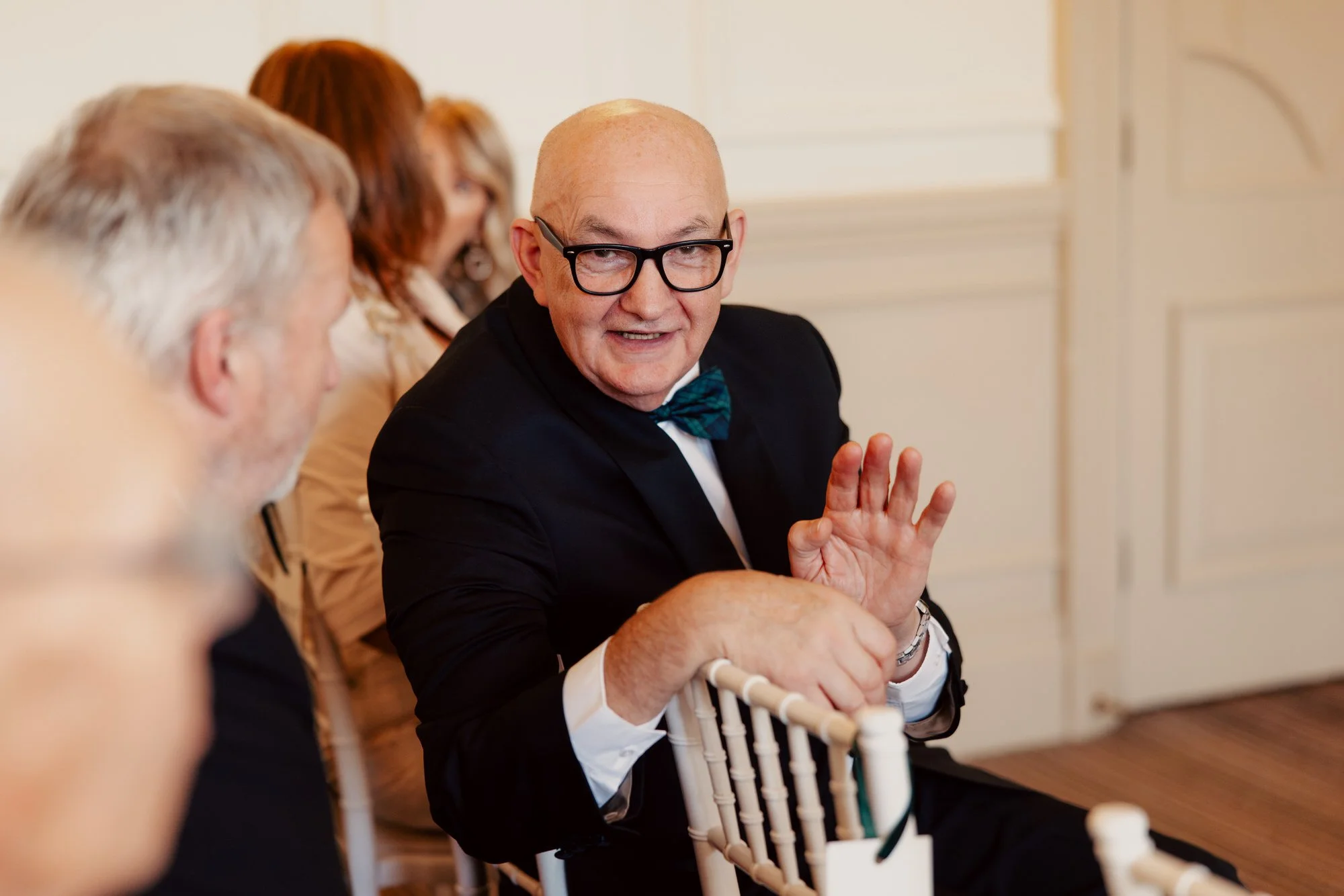 A seated wedding guest smiling and applauding.