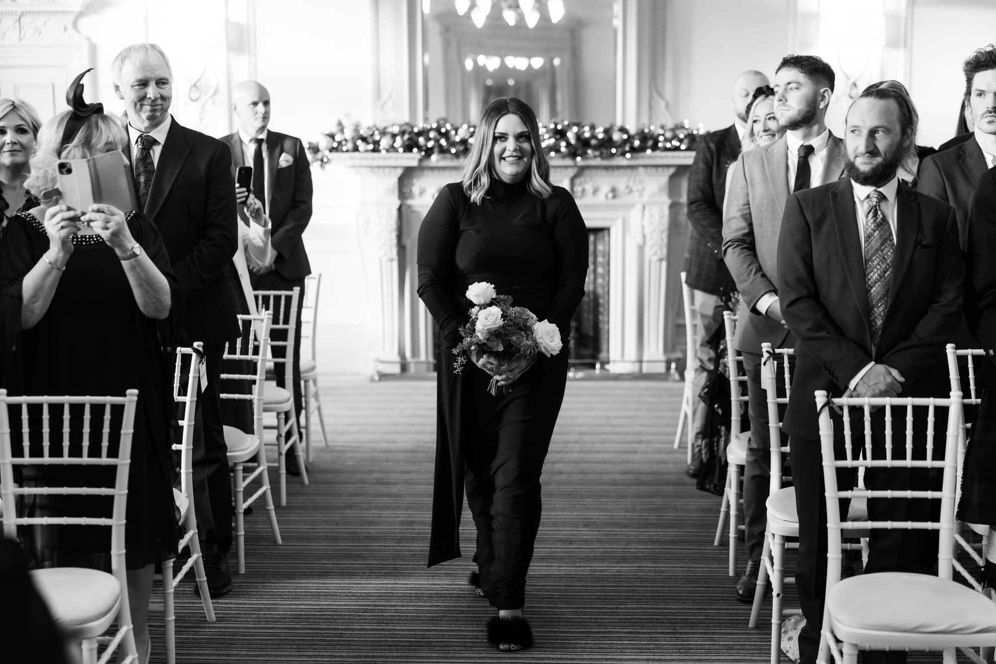 Black-and-white photograph of a bridesmaid walking down the aisle.
