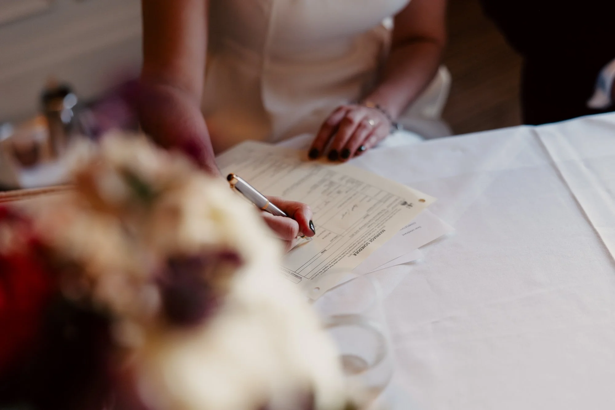 Close-up of a hand signing the wedding paperwork.