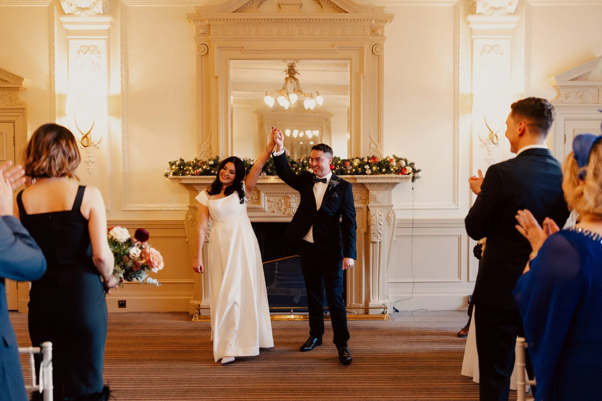 The newlyweds raising their joined hands as guests applaud.
