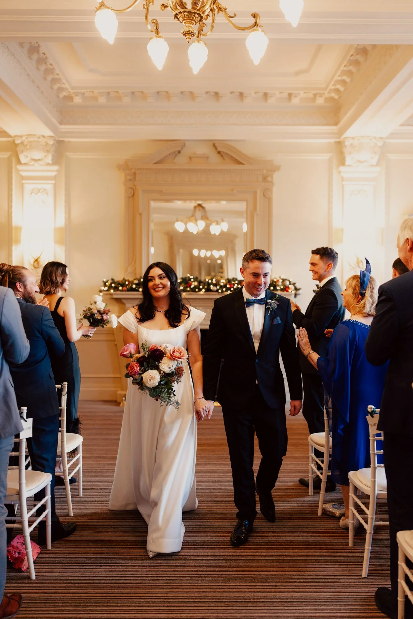 Milly and Vincent walking together between rows of guests.