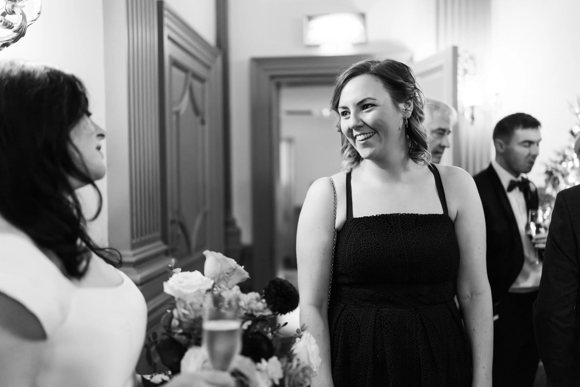 Black-and-white photograph of guests chatting over drinks.