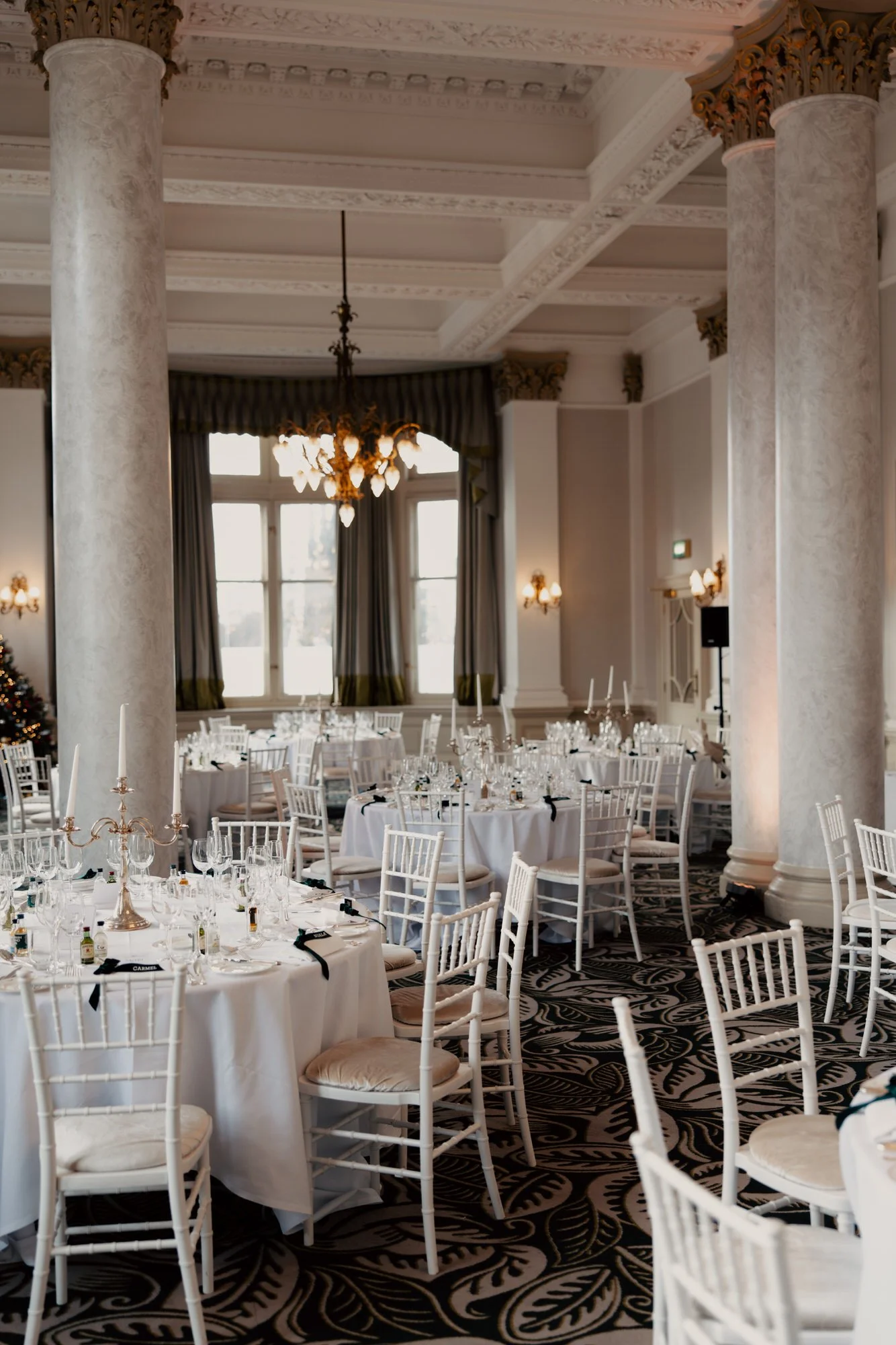Wedding breakfast tables set beneath chandeliers at the hotel.