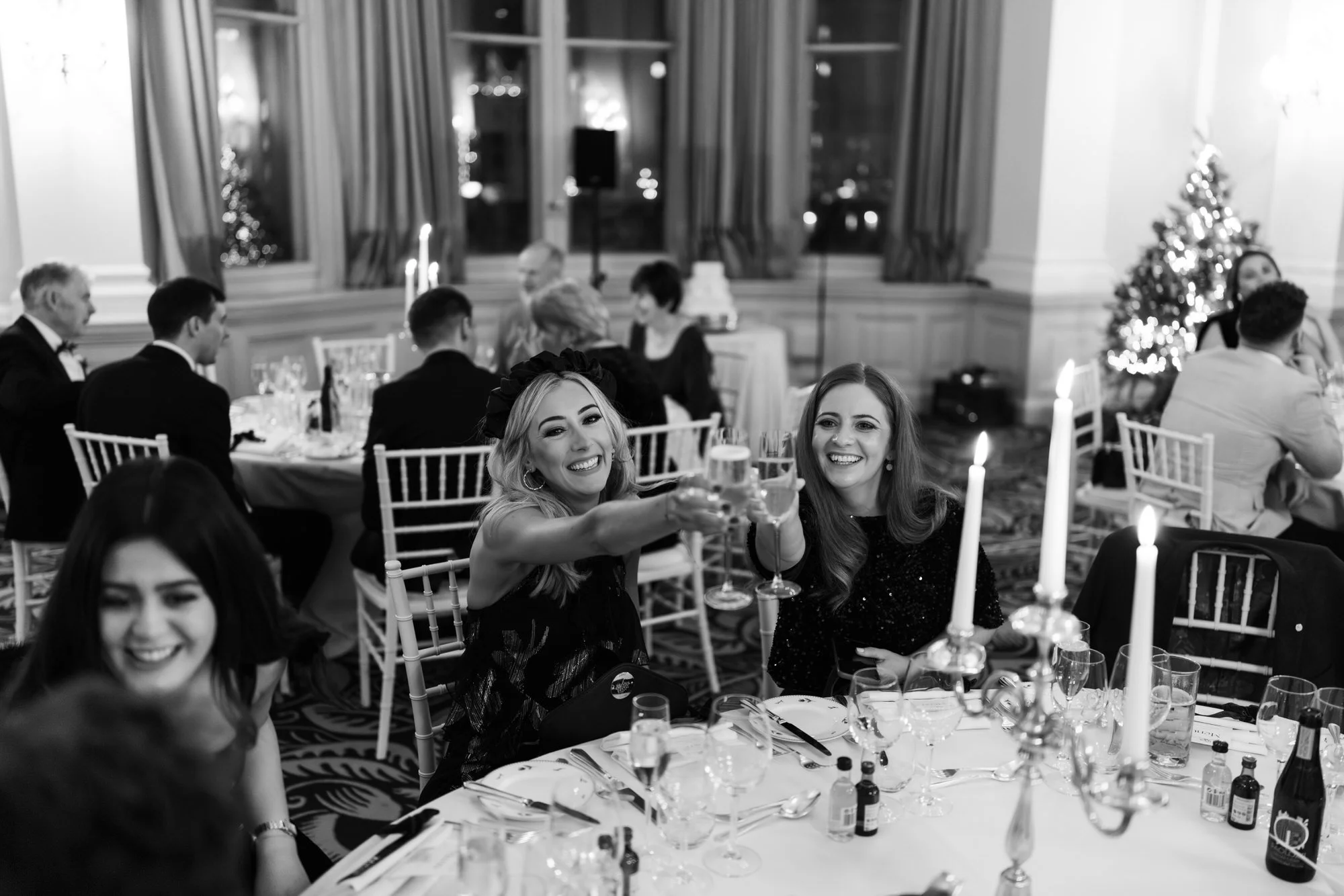 Black-and-white photograph of guests smiling around a candlelit table.