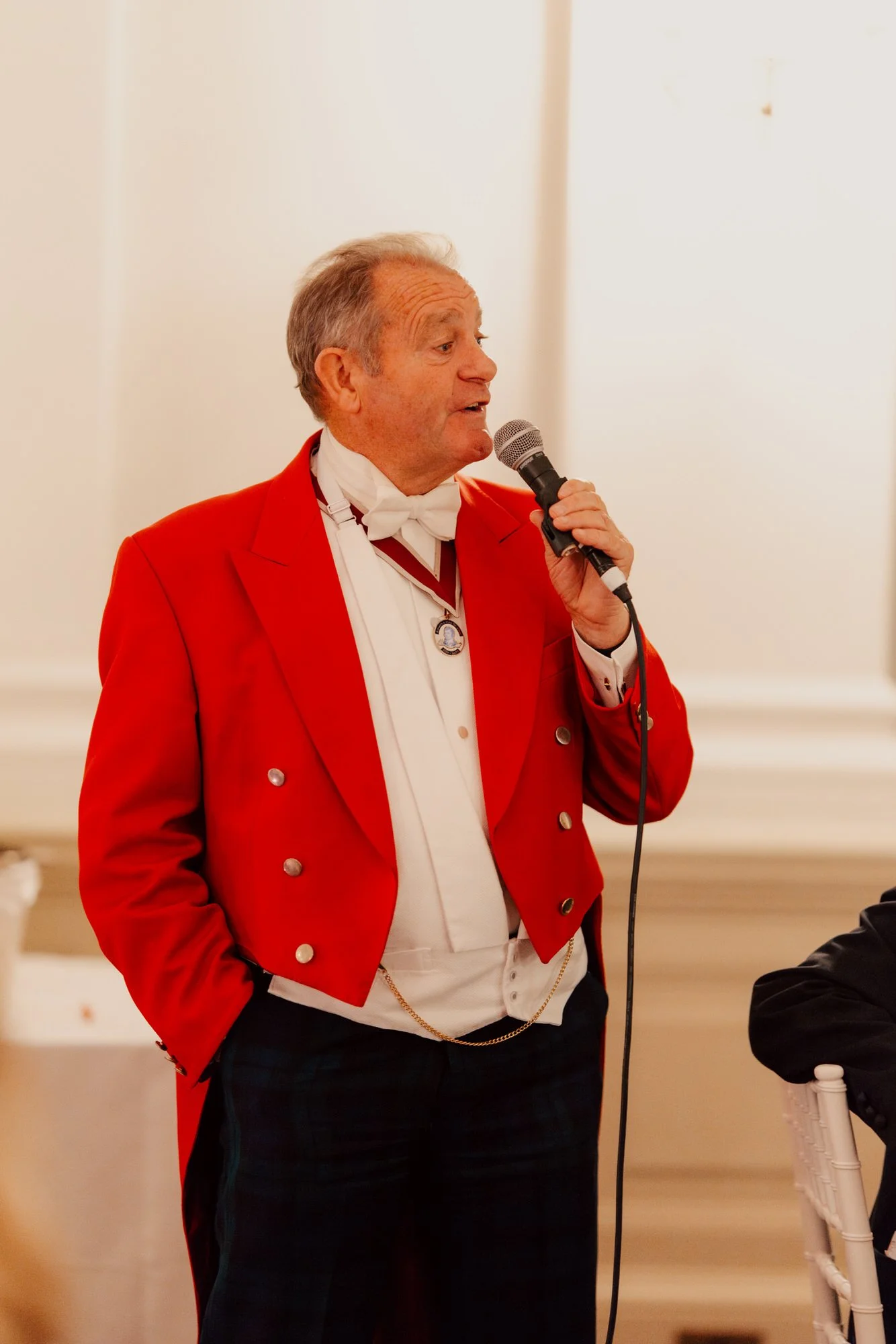 A man in a red jacket speaking into a microphone.
