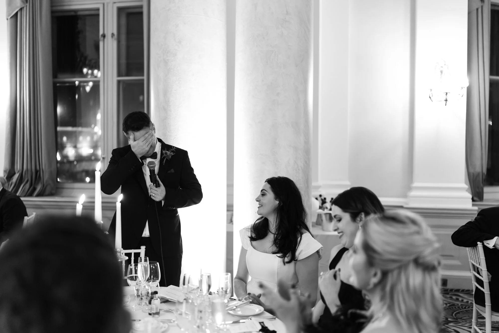 Black-and-white photograph of Vincent speaking beside Milly at the table.