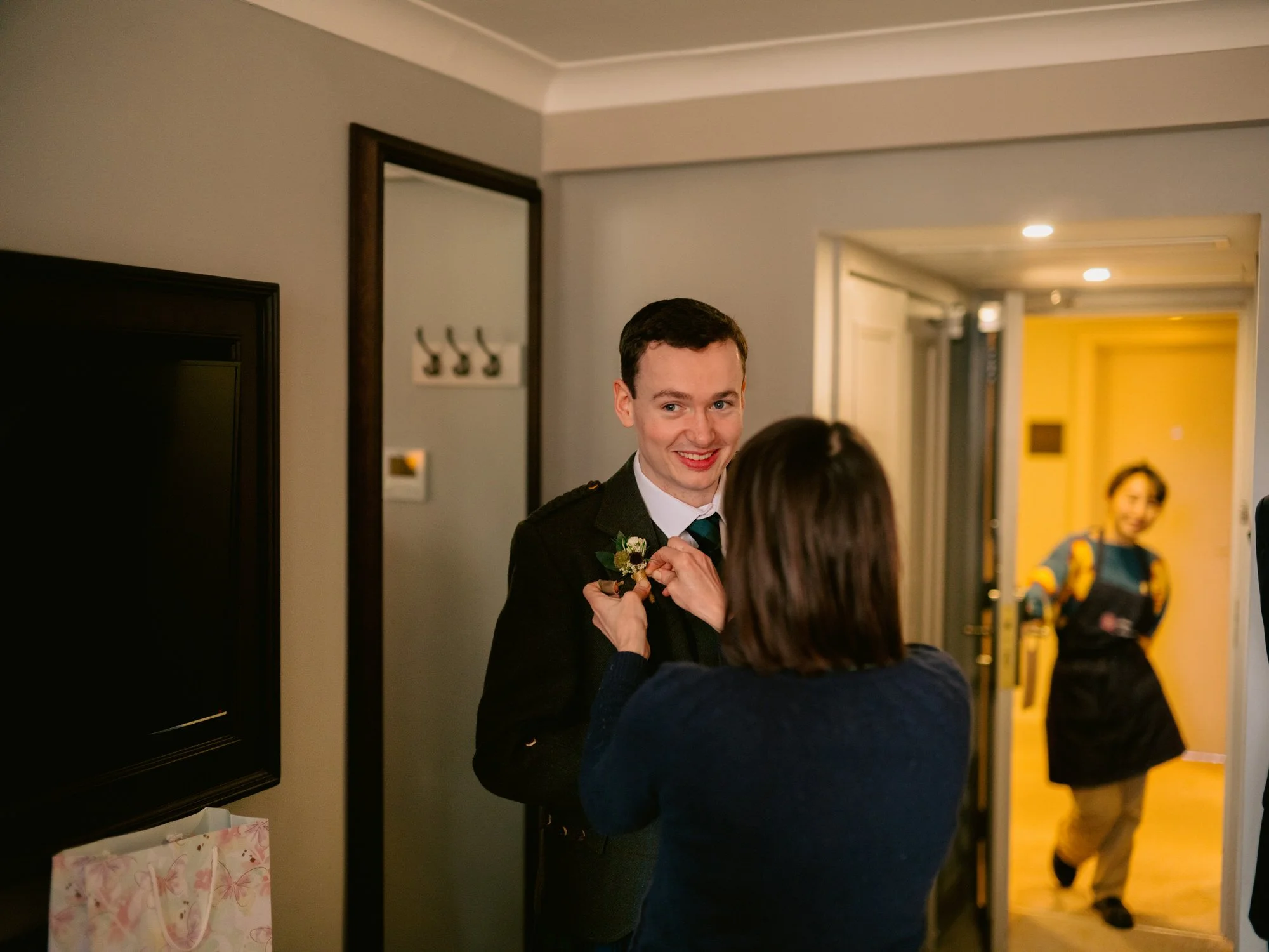 Fraser smiling as a guest adjusts his wedding outfit