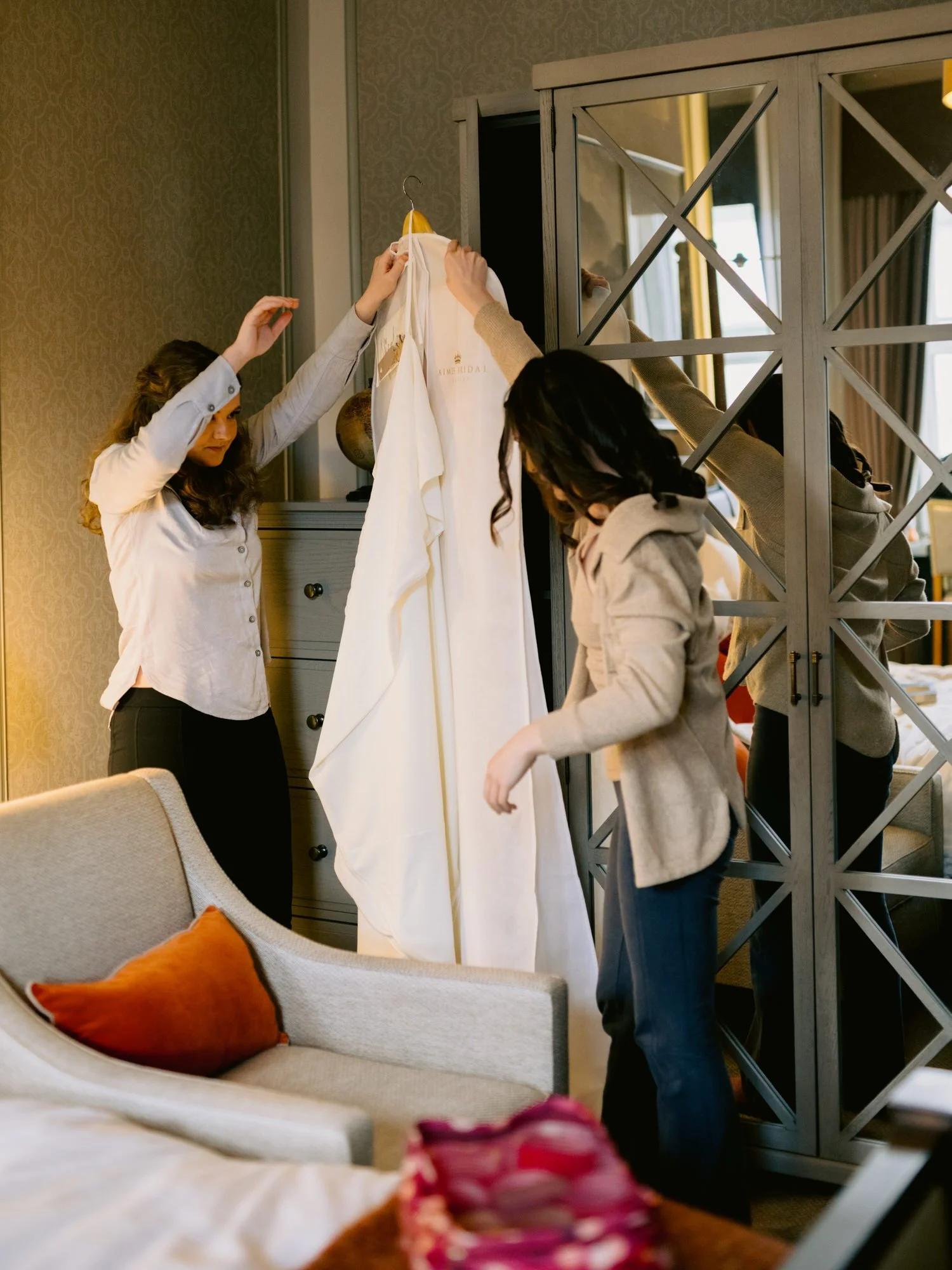 The wedding dress being lifted from its hanger in the hotel room