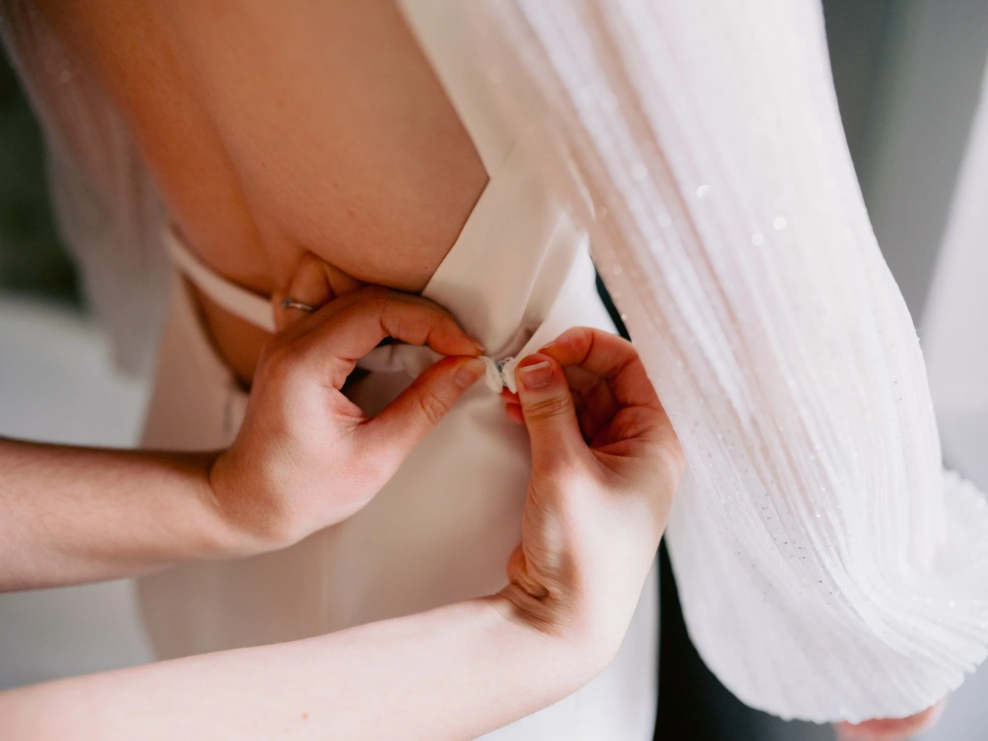 Close-up of the buttons being fastened on Nicola’s wedding dress