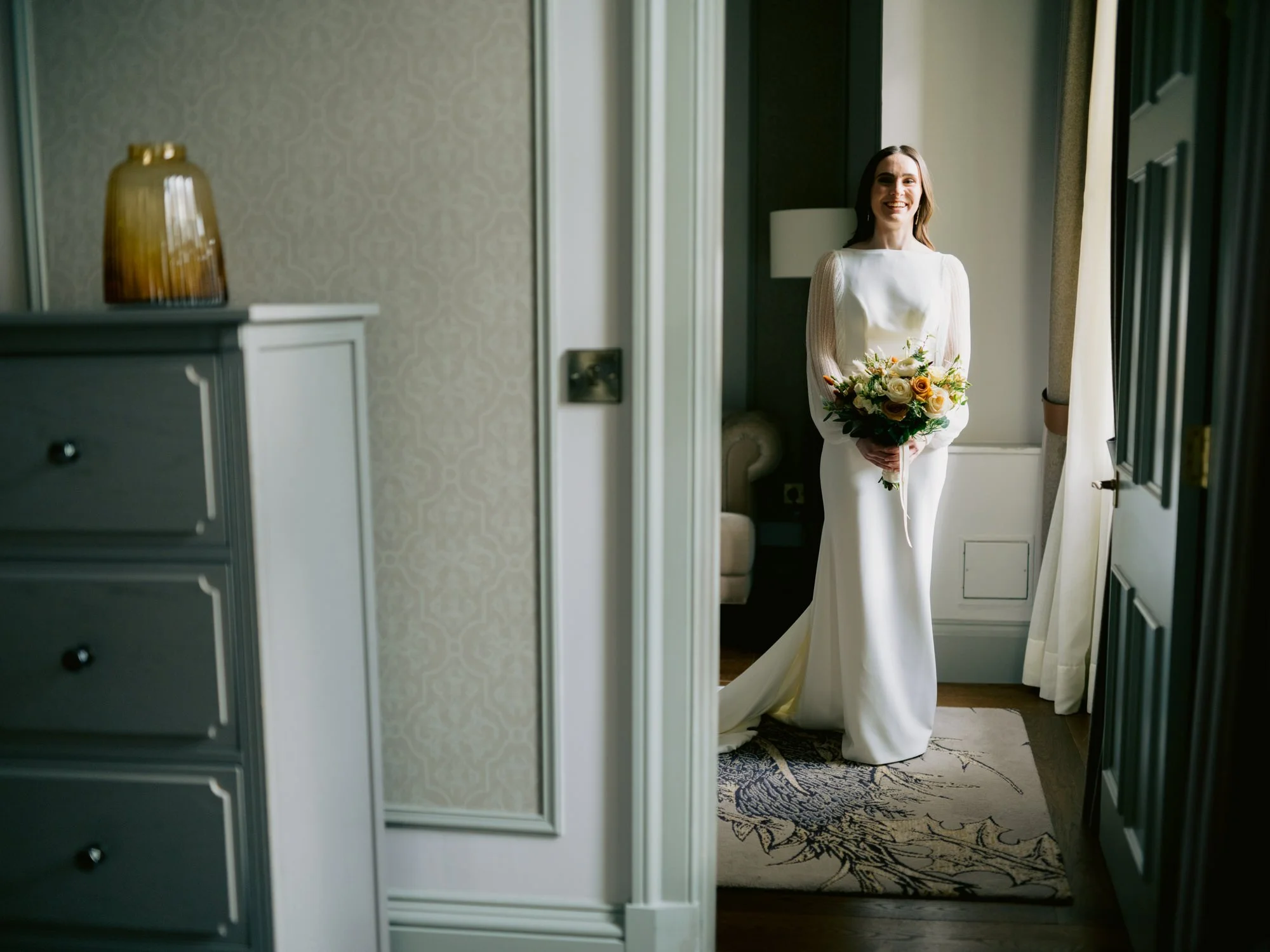 Nicola standing with her bouquet in the hotel doorway