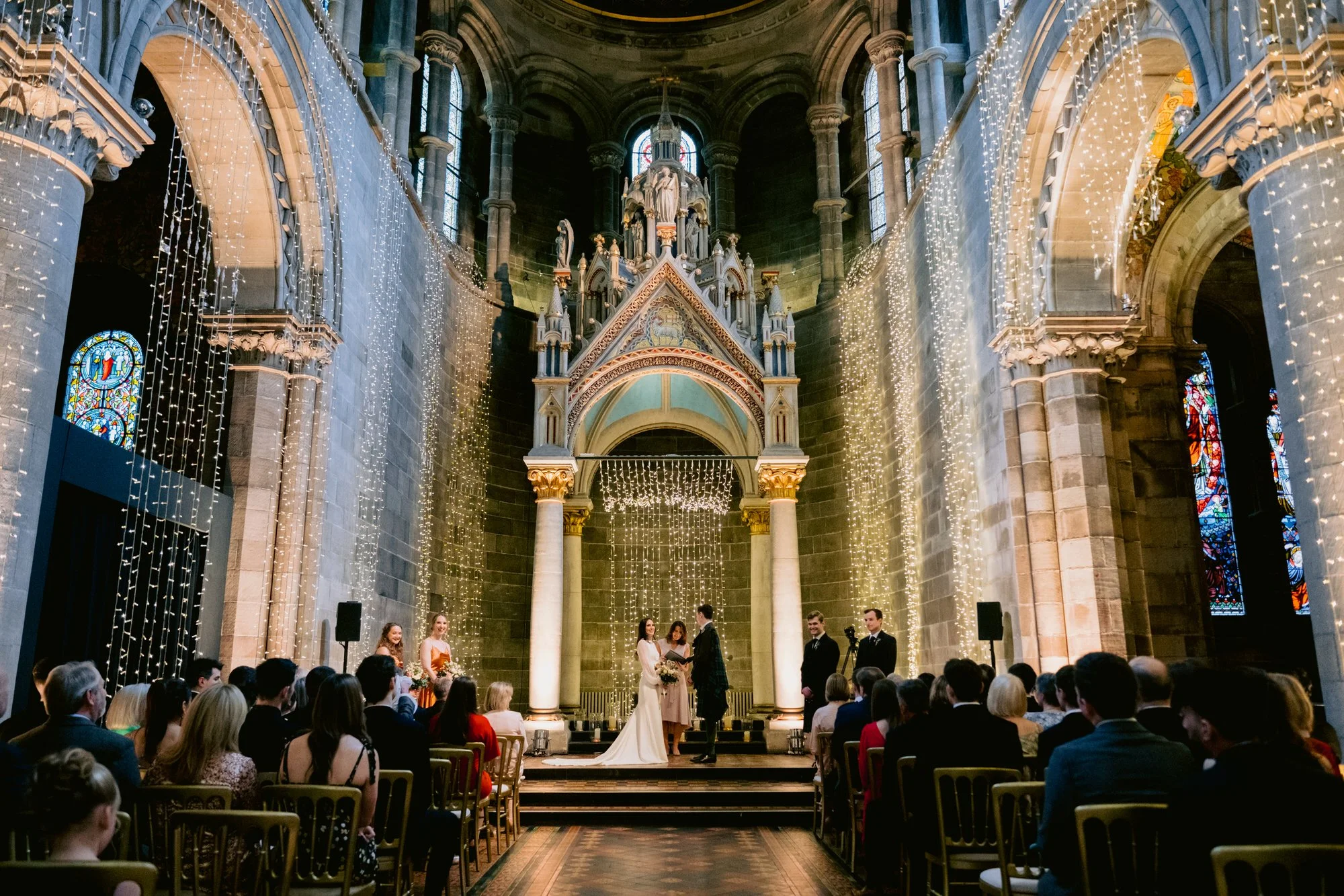 Wide view of the ceremony beneath Mansfield Traquair’s vaulted ceiling