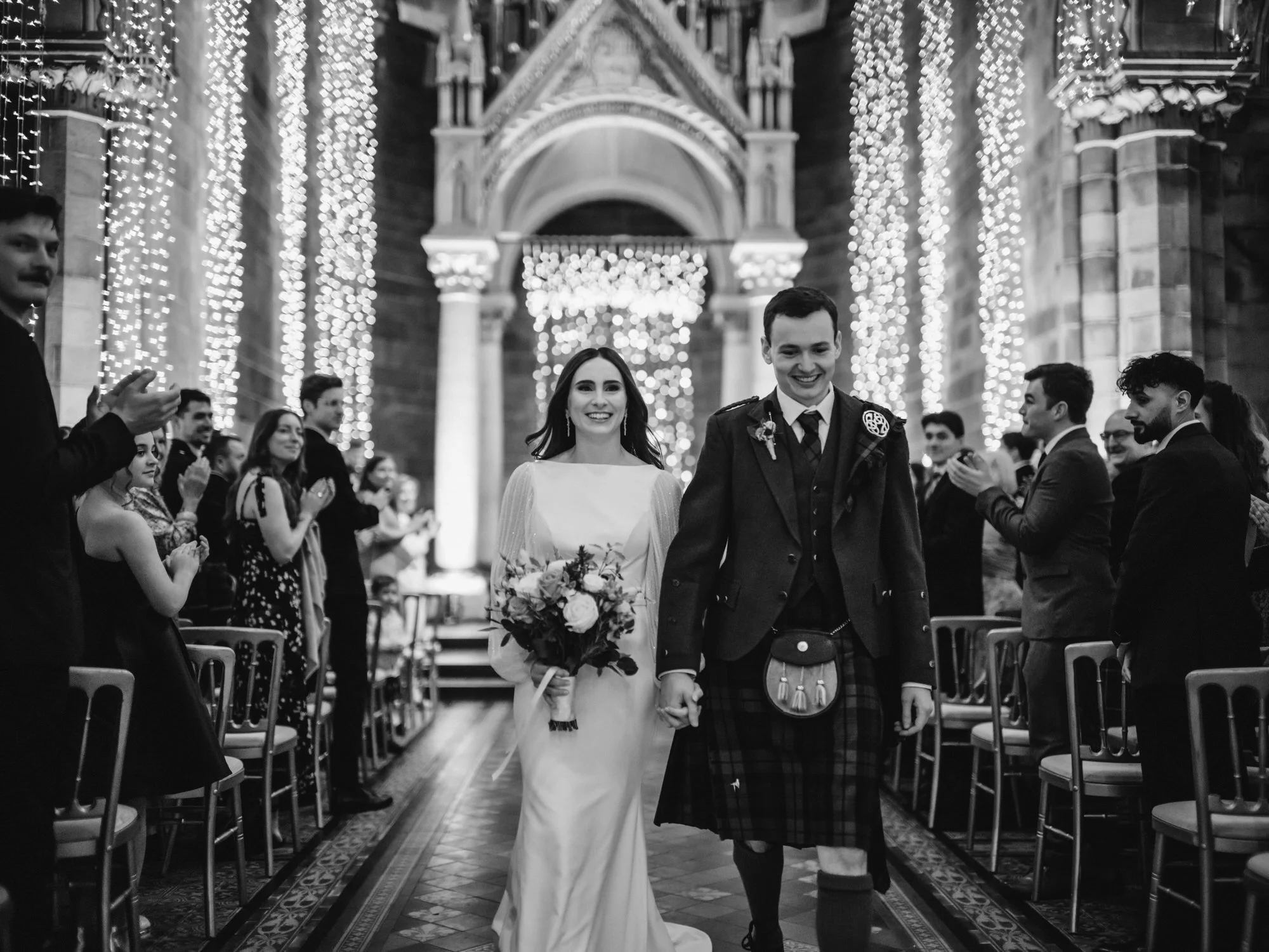 Black-and-white photograph of the newlyweds walking up the aisle