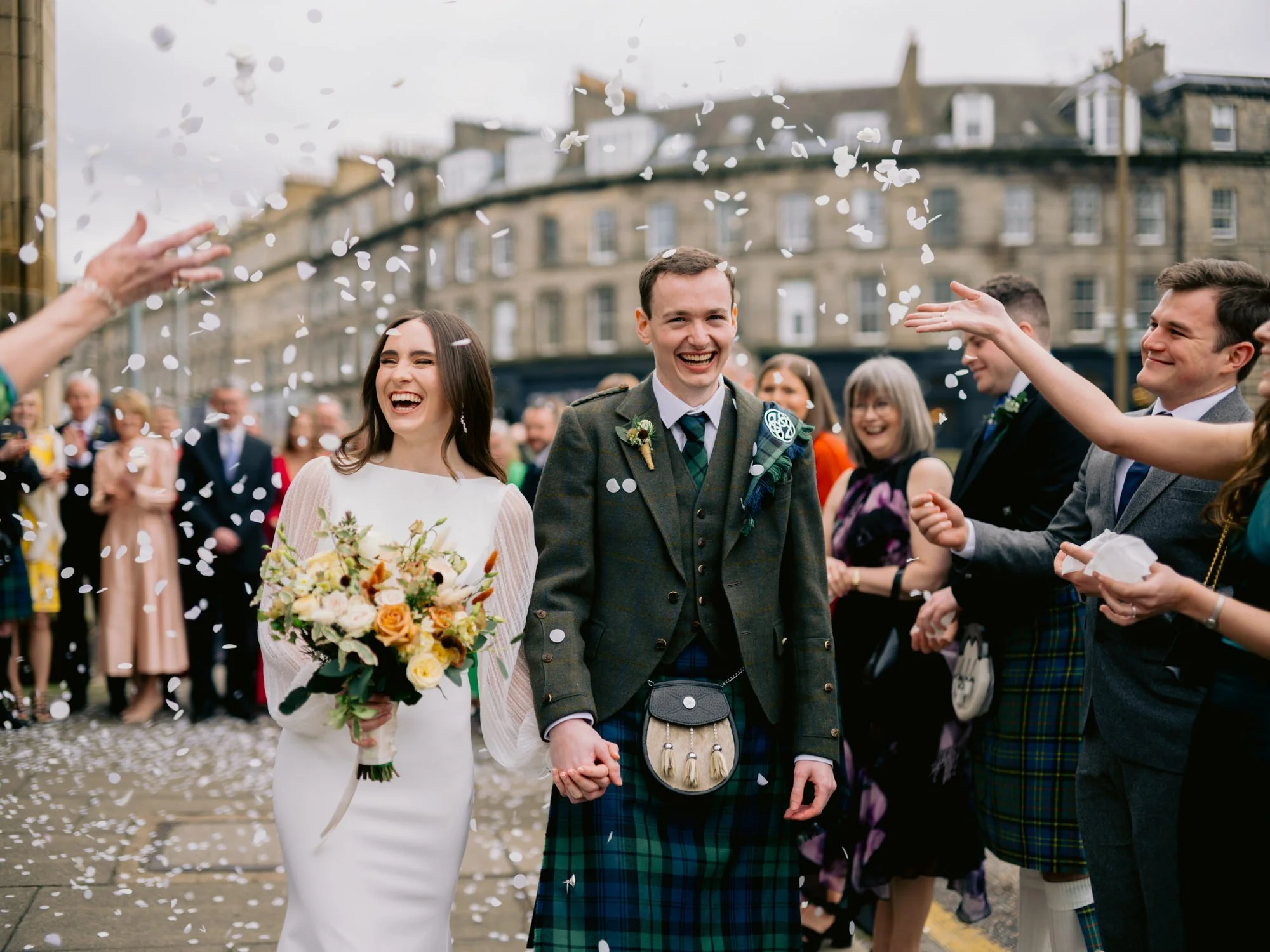 Nicola and Fraser laughing beneath a shower of confetti