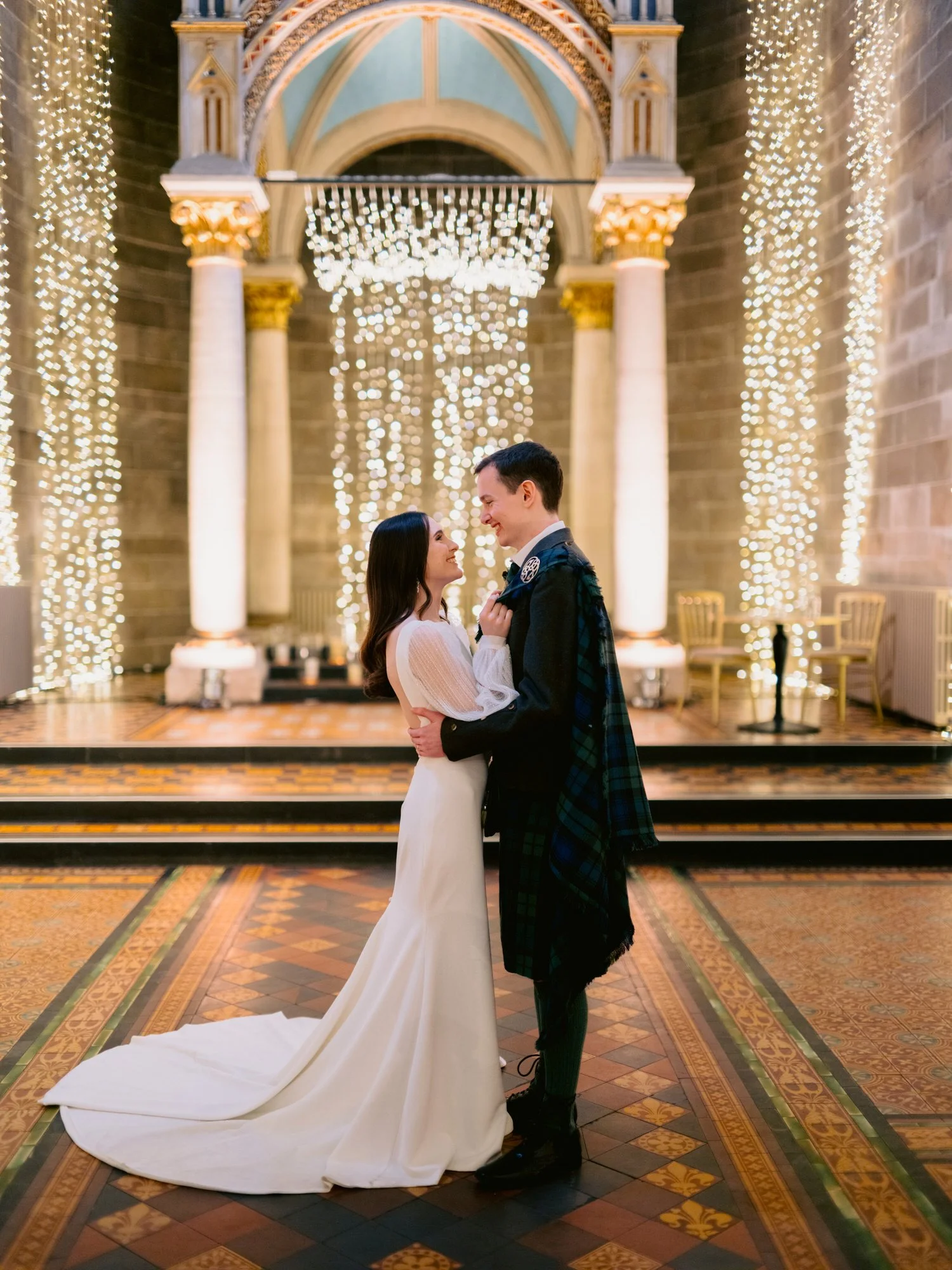 Full-length portrait of the couple beneath the illuminated canopy