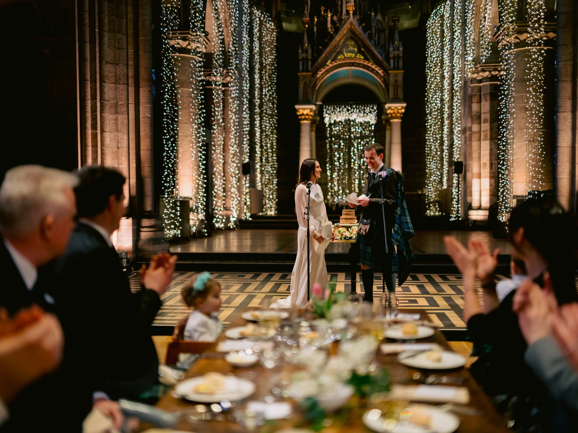 Nicola and Fraser standing together as guests watch from the tables