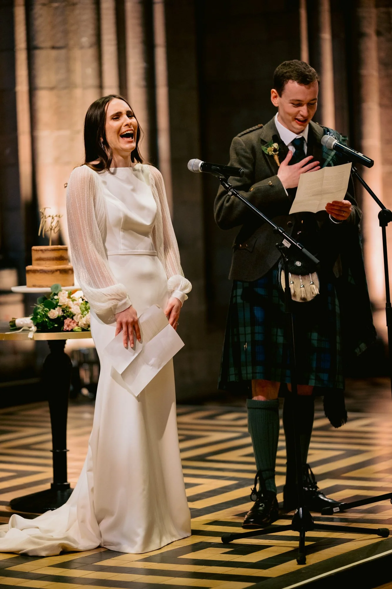 Nicola laughing while Fraser speaks into a microphone