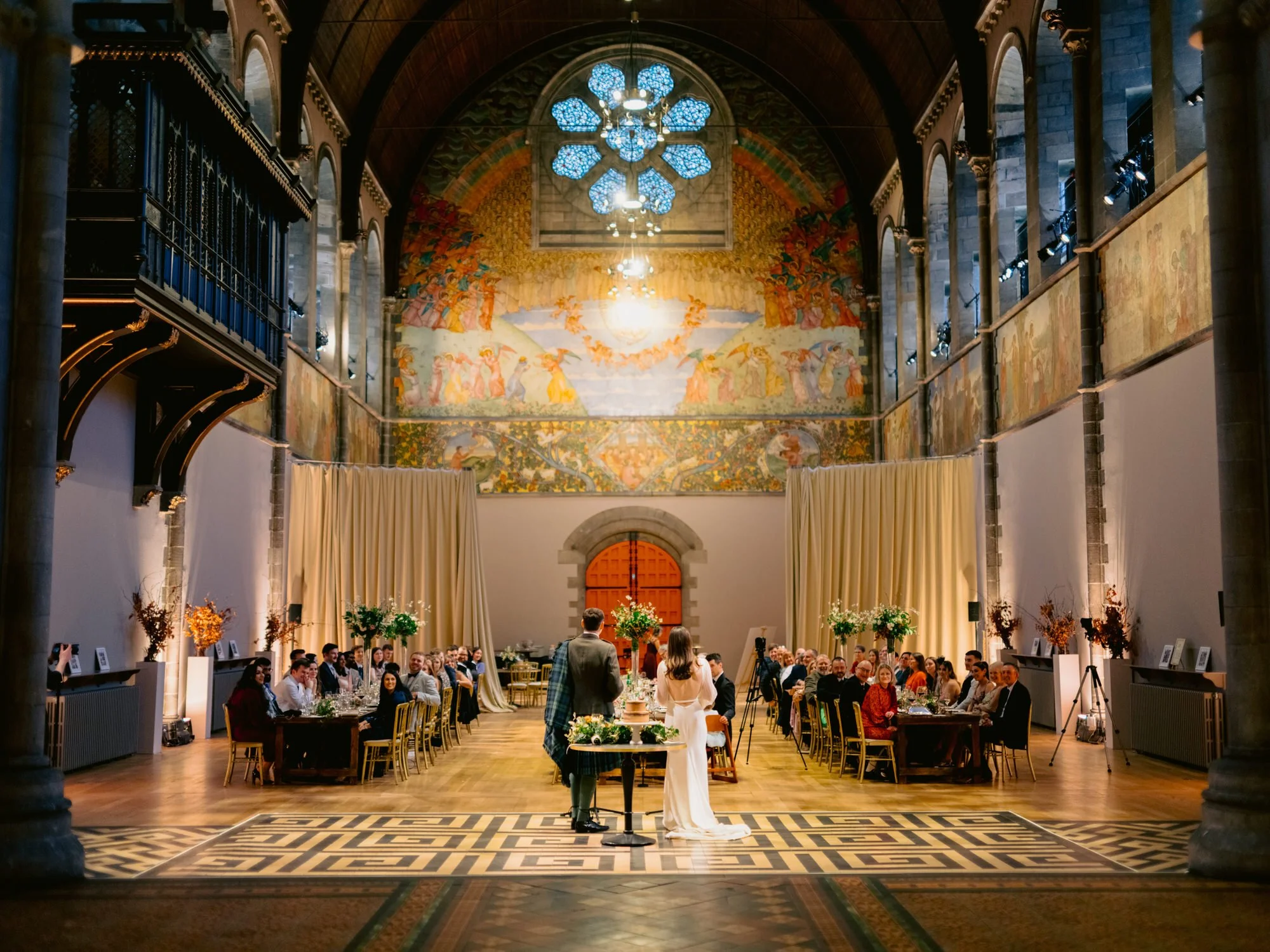 Wide view of the wedding breakfast beneath the painted walls