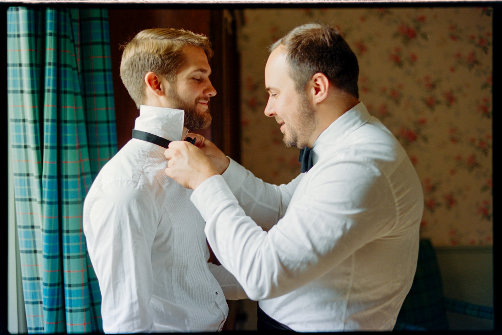 One groom helping the other with his bow tie during preparations at Thirlestane Castle.