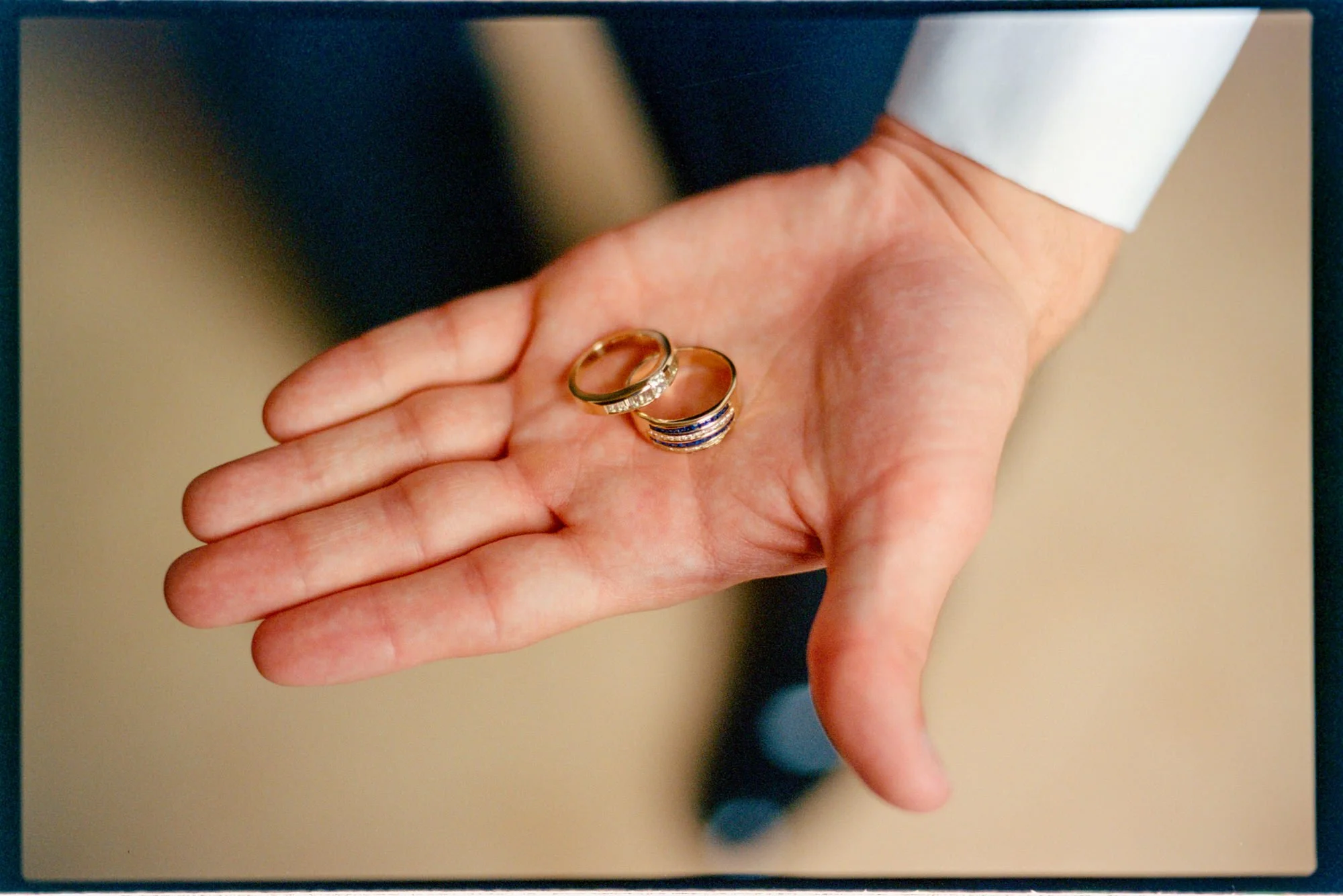 Two gold wedding rings held in an open palm.