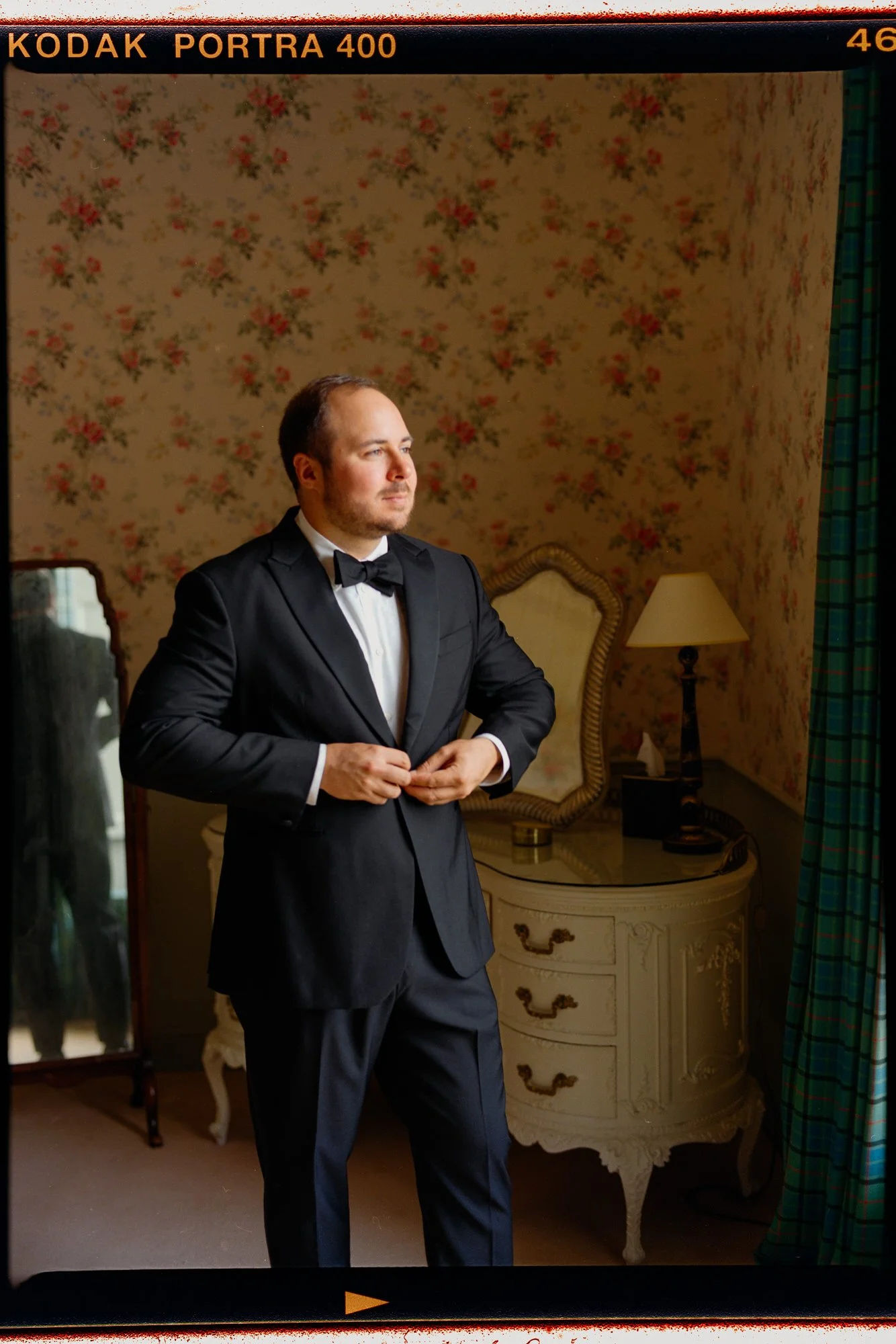 Film portrait of a groom standing beside a dresser at Thirlestane Castle.