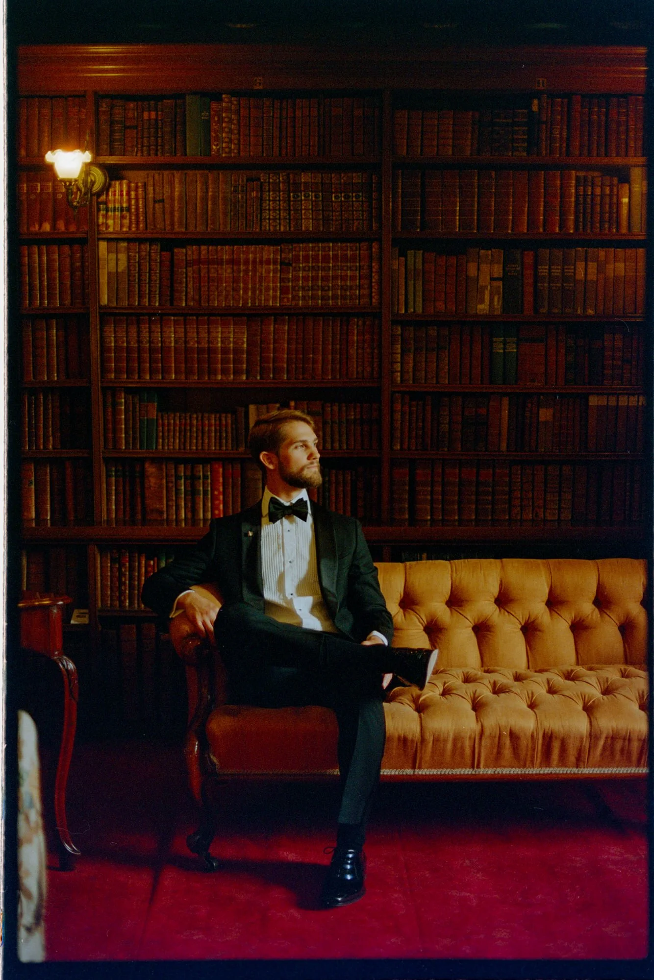A groom seated on an ochre sofa in front of bookshelves at Thirlestane Castle.