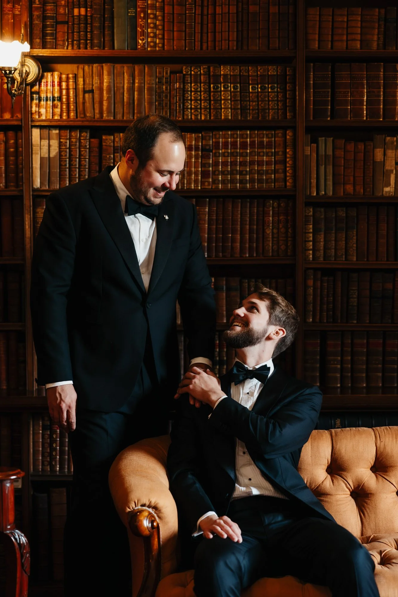 A groom looking up at his partner from a sofa in the castle library.