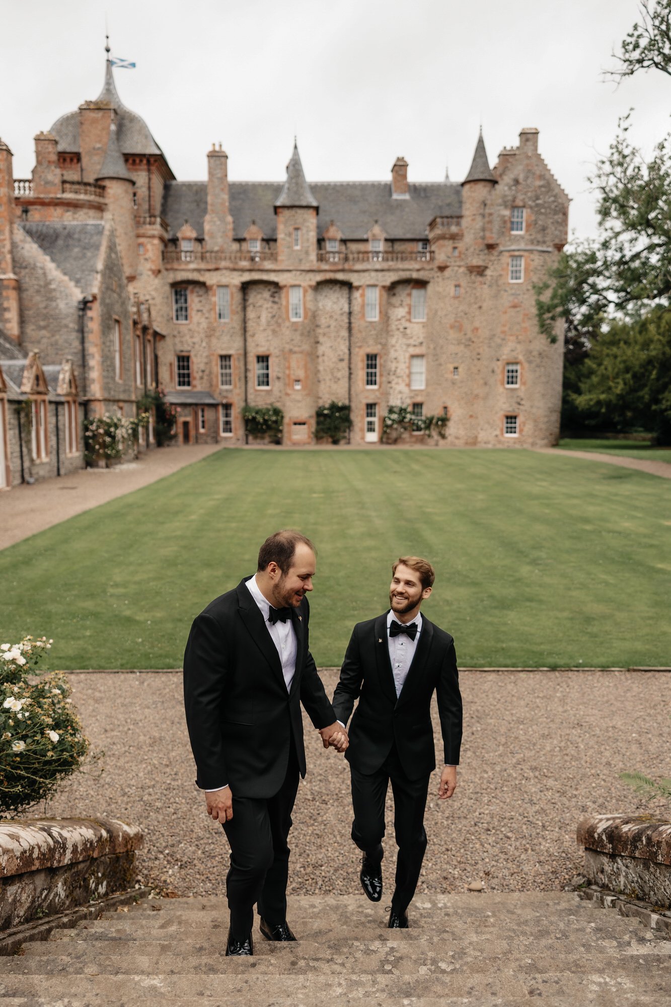 The grooms walking up stone steps with Thirlestane Castle behind them.