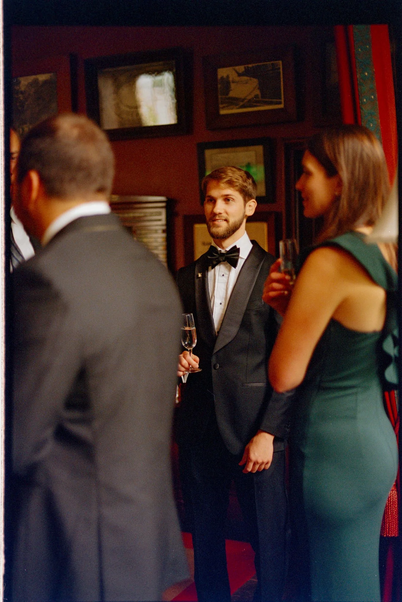 A groom holding a drink while chatting with friends inside the castle.