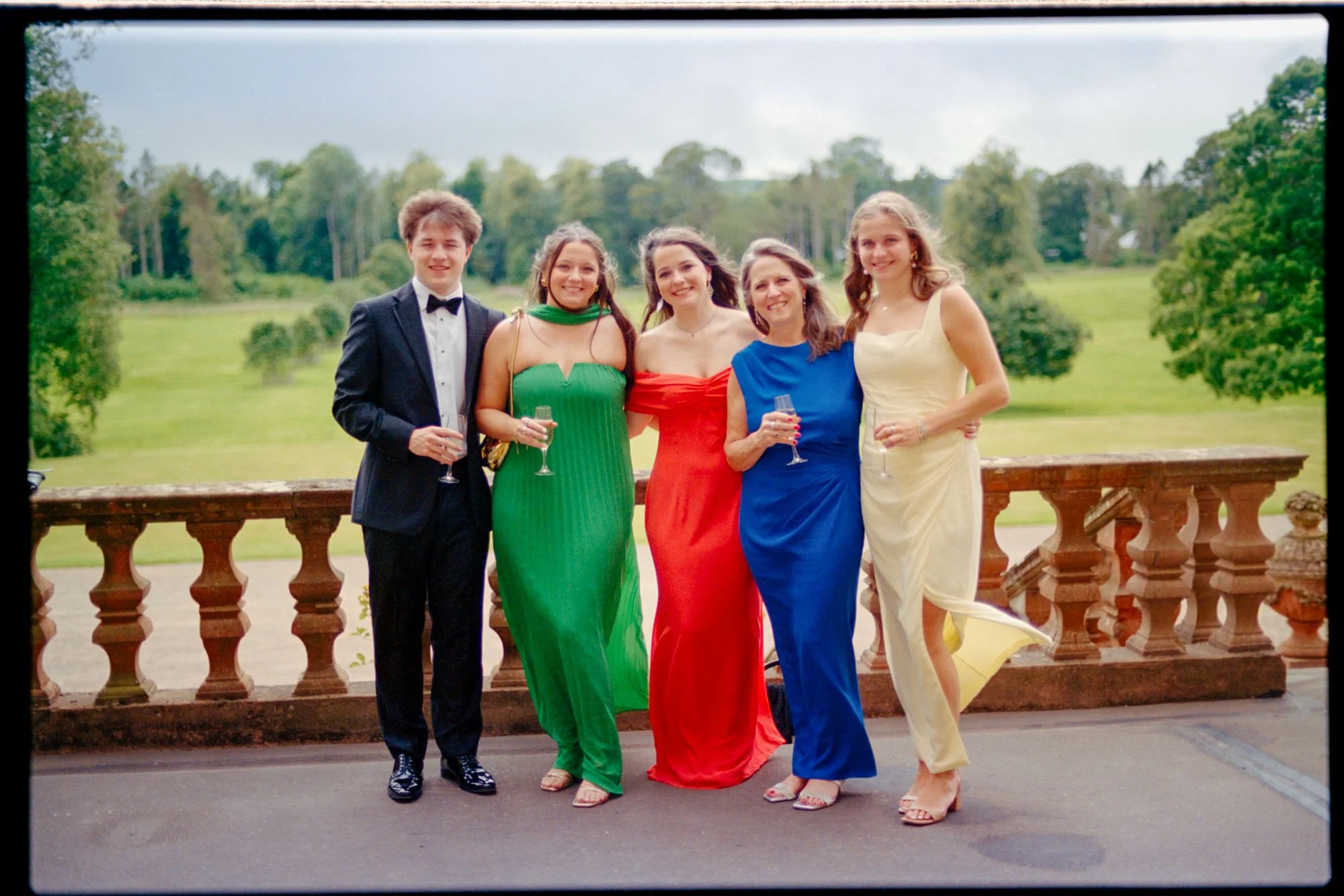 Five wedding guests posing with drinks on the castle terrace.