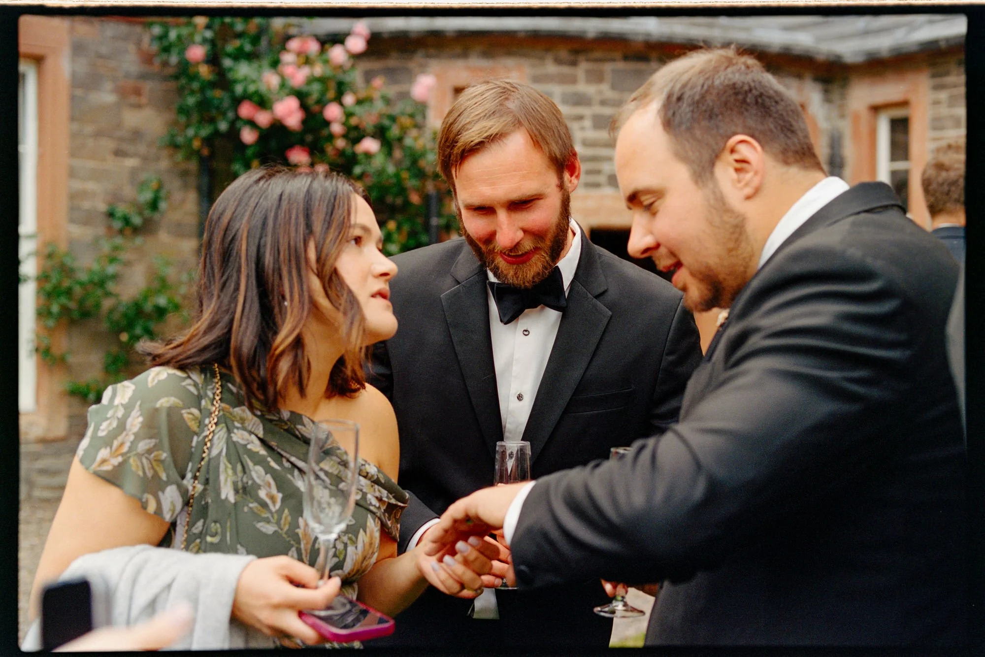 The newlyweds talking with a guest beside the castle's climbing roses.