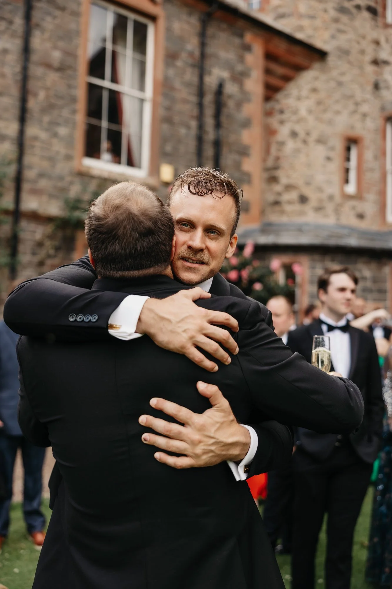 A newlywed embracing a guest outside Thirlestane Castle.