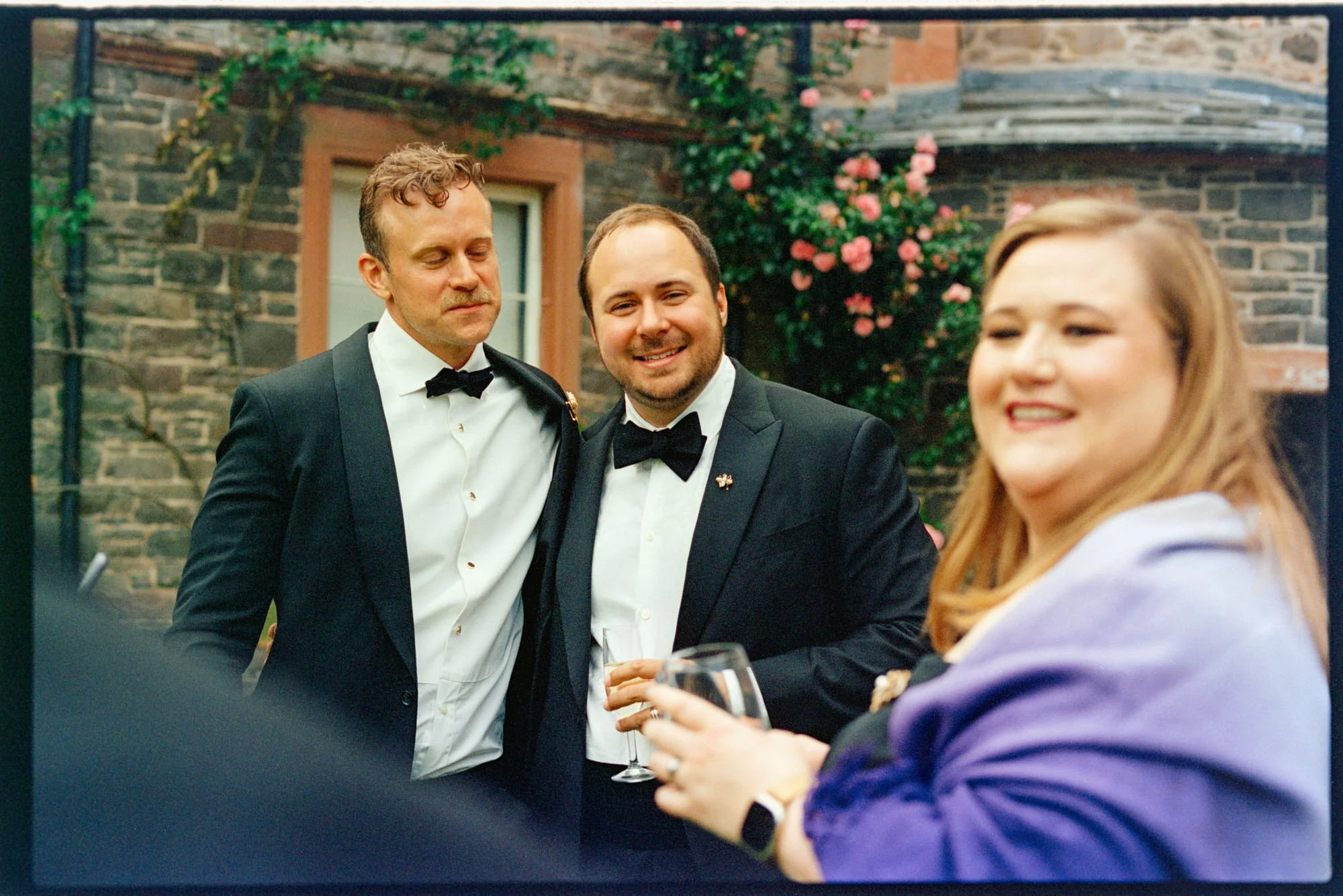 A newlywed smiling with guests during the outdoor drinks reception.