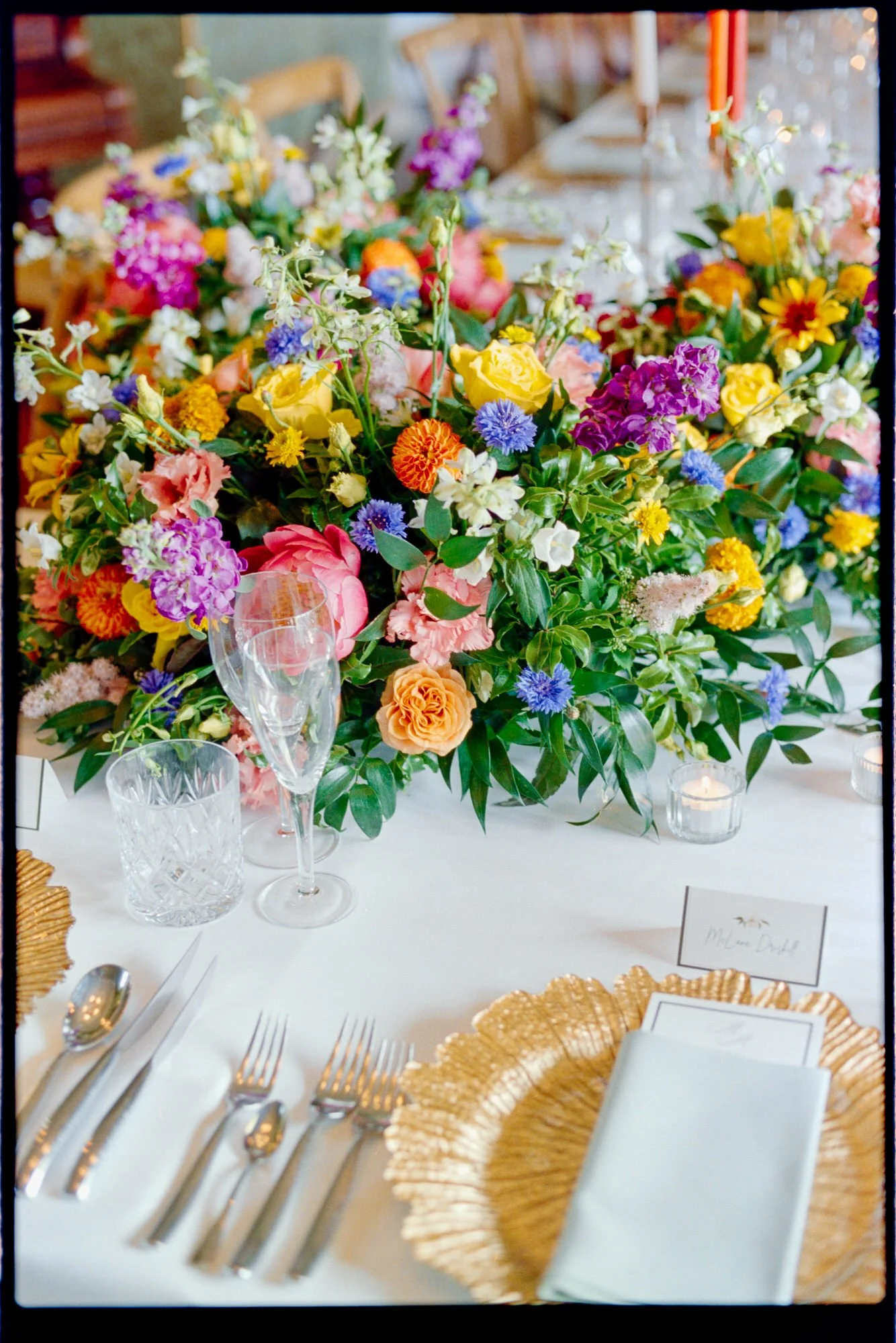 Colourful flowers, gold-edged plates and neatly folded napkins on the wedding table.