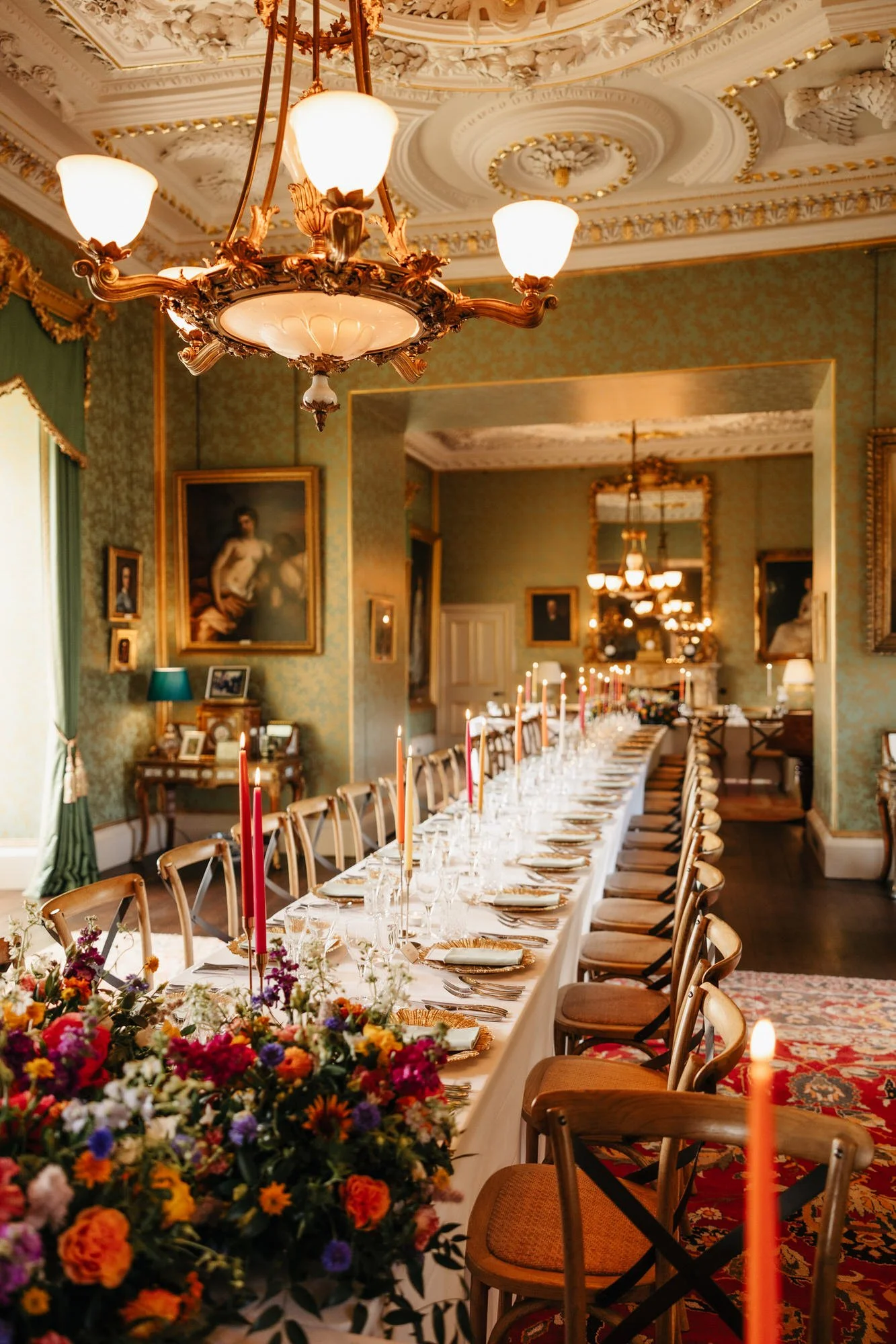 A view along the dinner table towards a window and ornate castle ceiling.