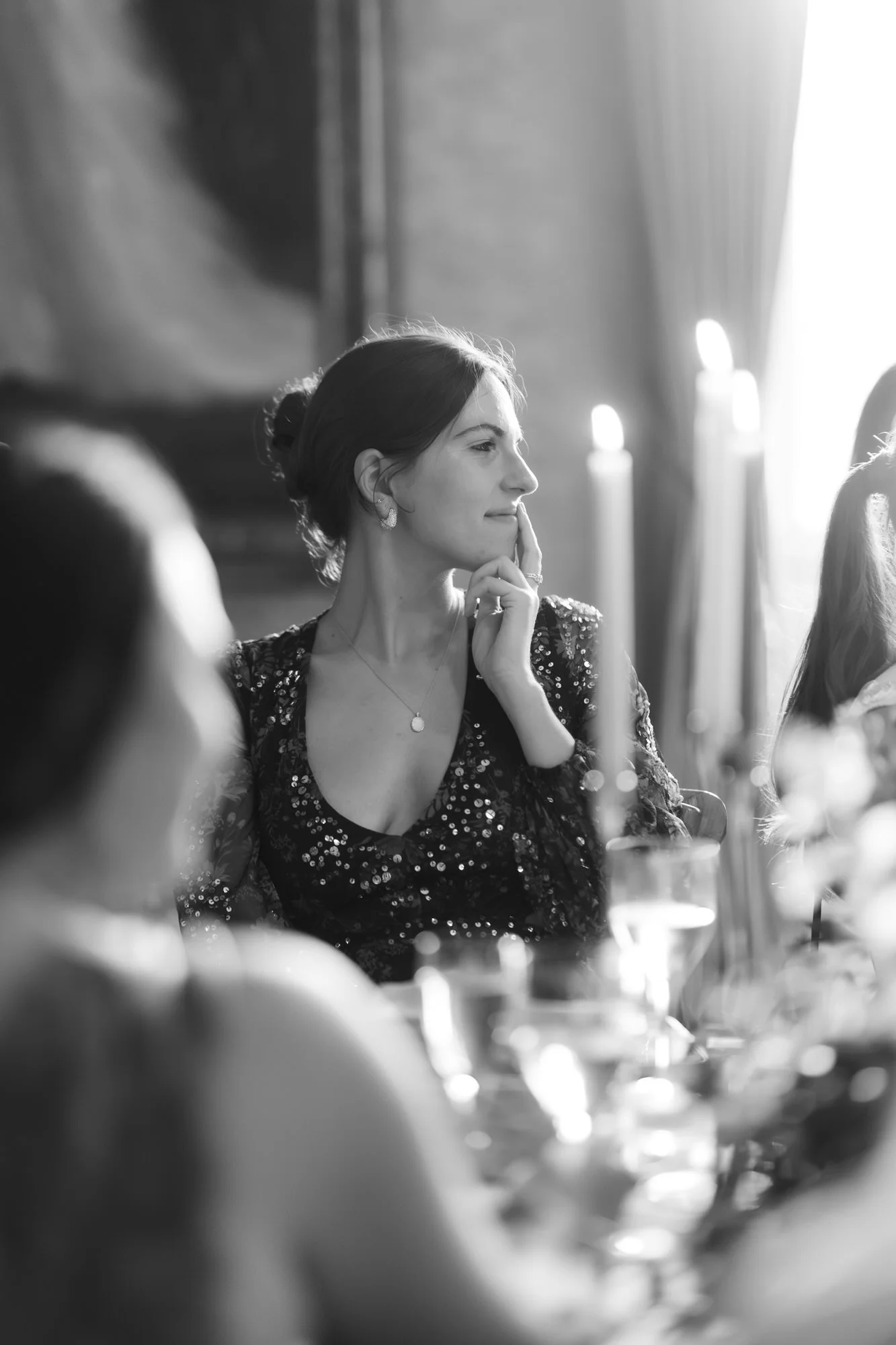 A guest smiling at the candlelit dinner table in black and white.