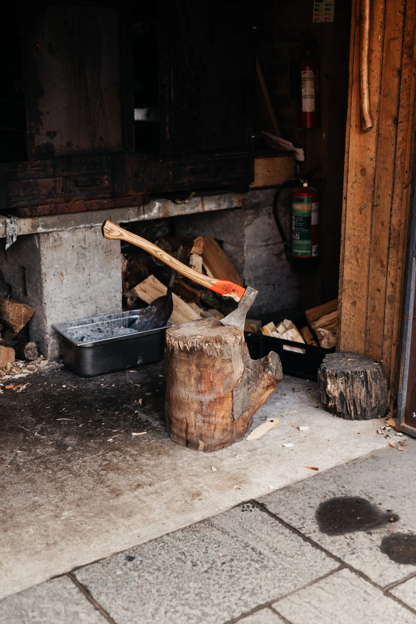 A wood-burning stove beside stacked logs at the farm