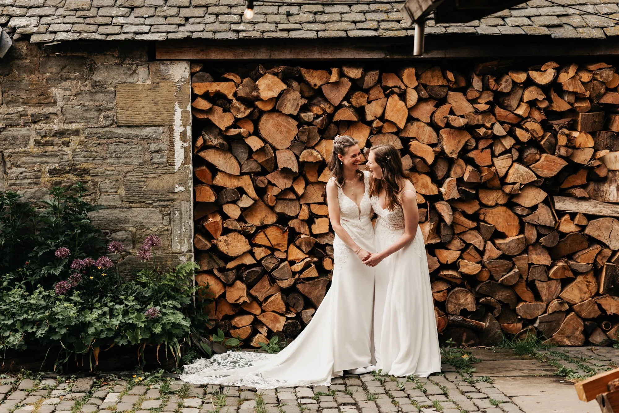 Jackie and Briony beside the stacked logs at The Free Company