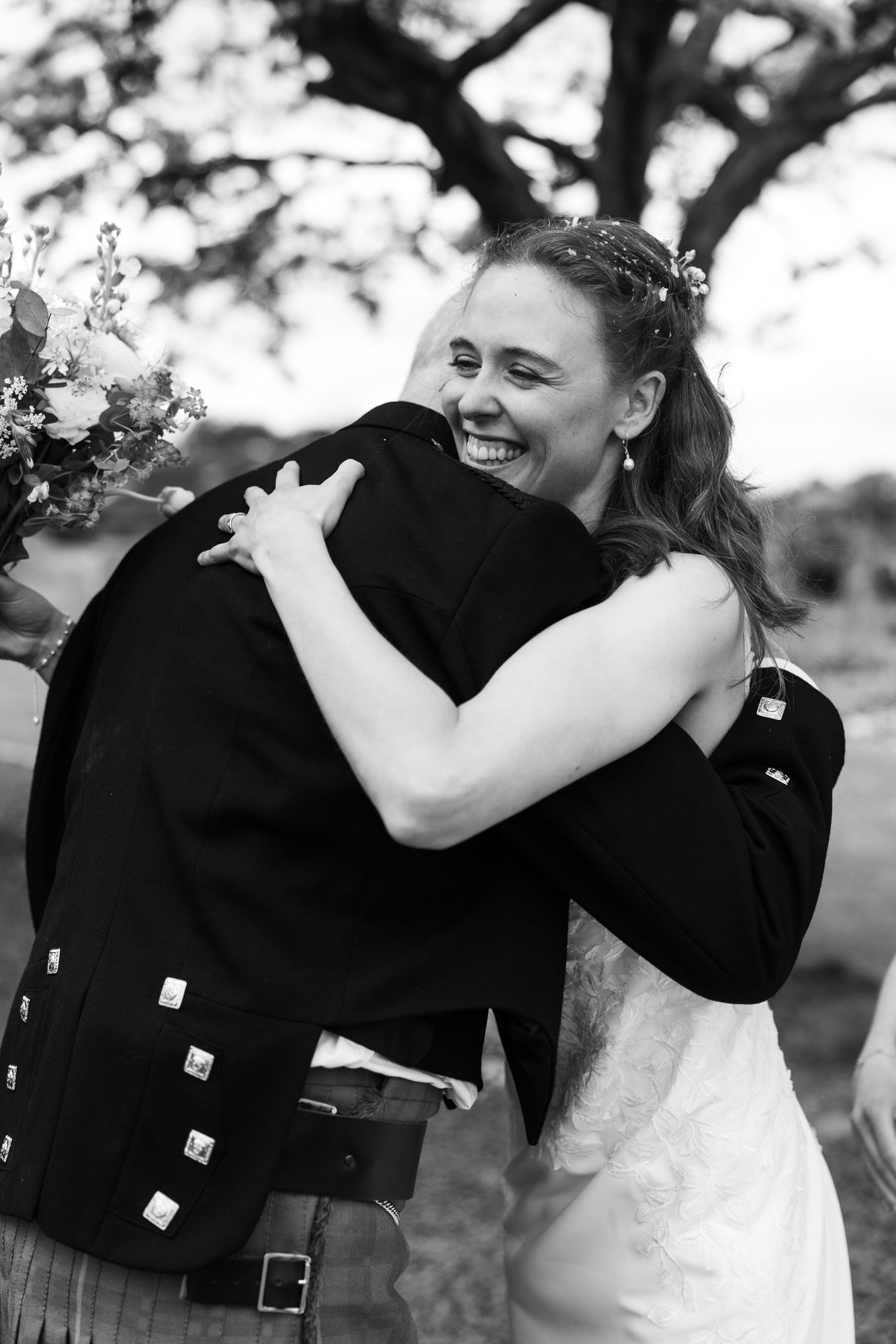 A bride embracing a friend in black and white