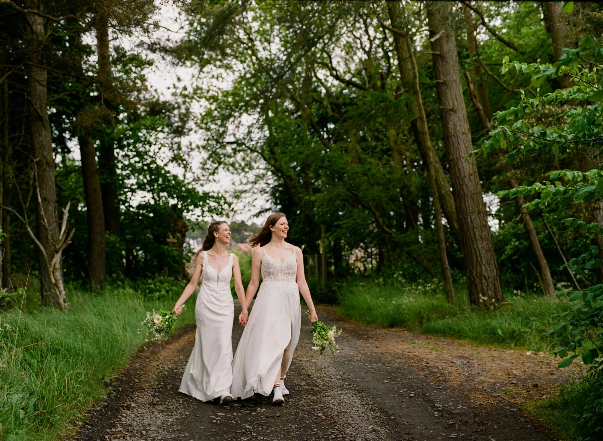The brides walking together beneath the trees
