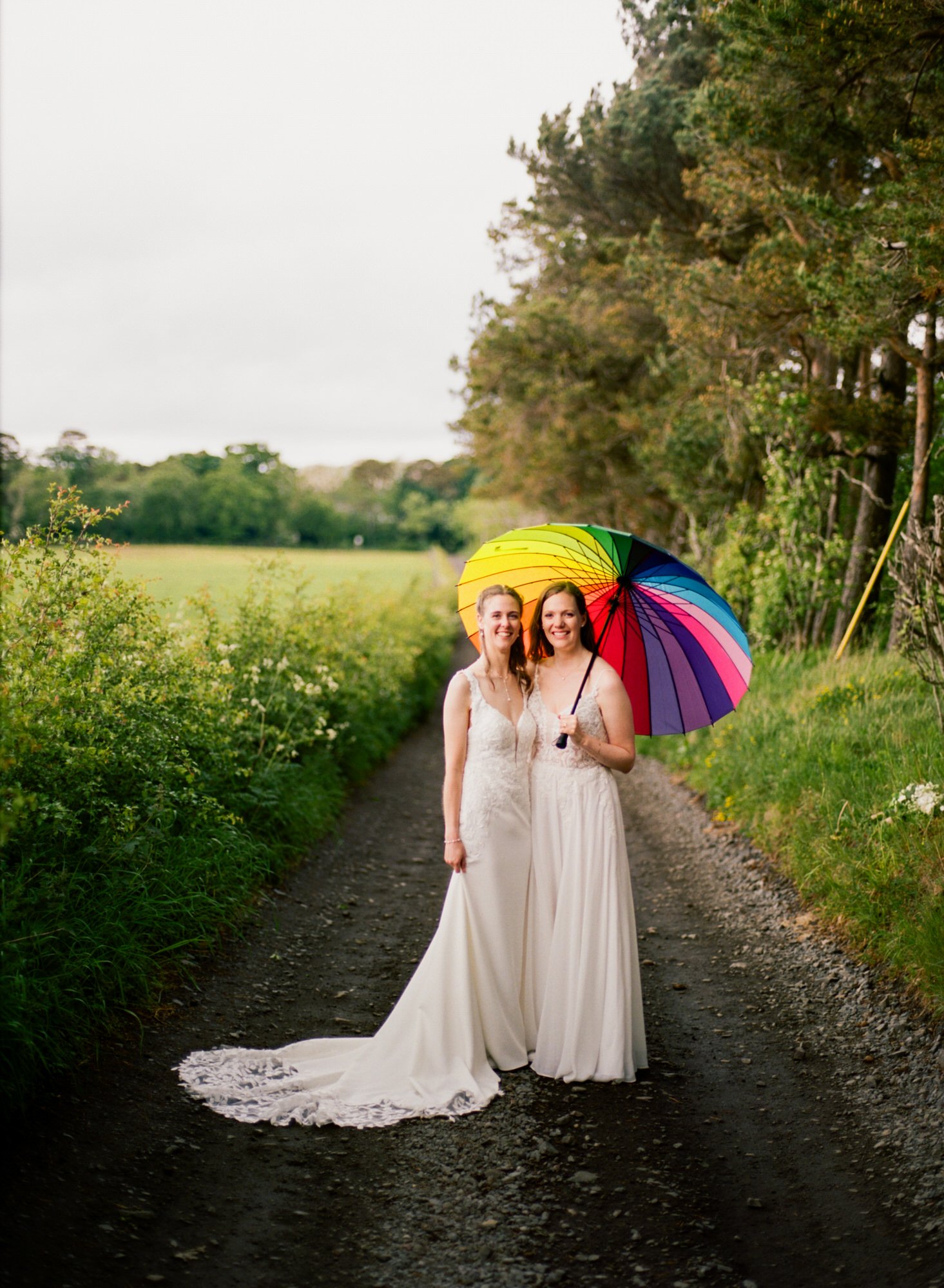 Jackie and Briony beneath a rainbow umbrella